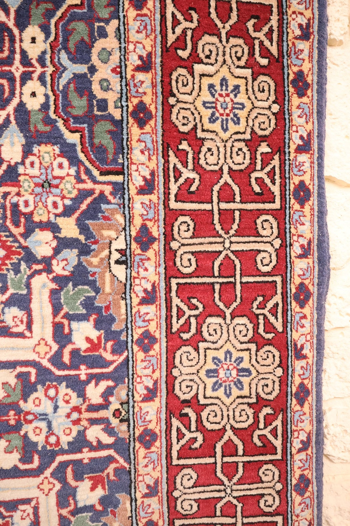 Bordure rouge à entrelacs ivoire et contre-bordures beige fleuries du tapis Hereke