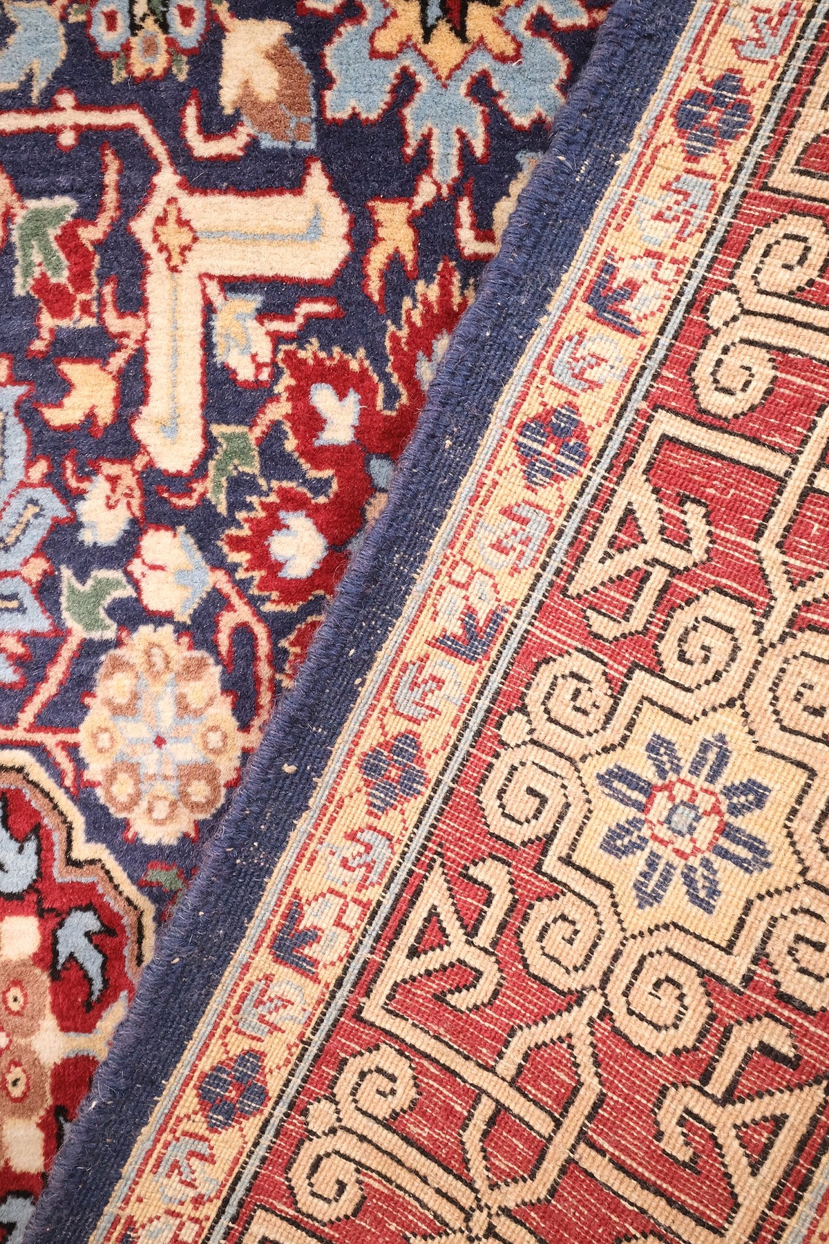 Coin replié du tapis Hereke, envers et nœuds visibles le long de la lisière bleue