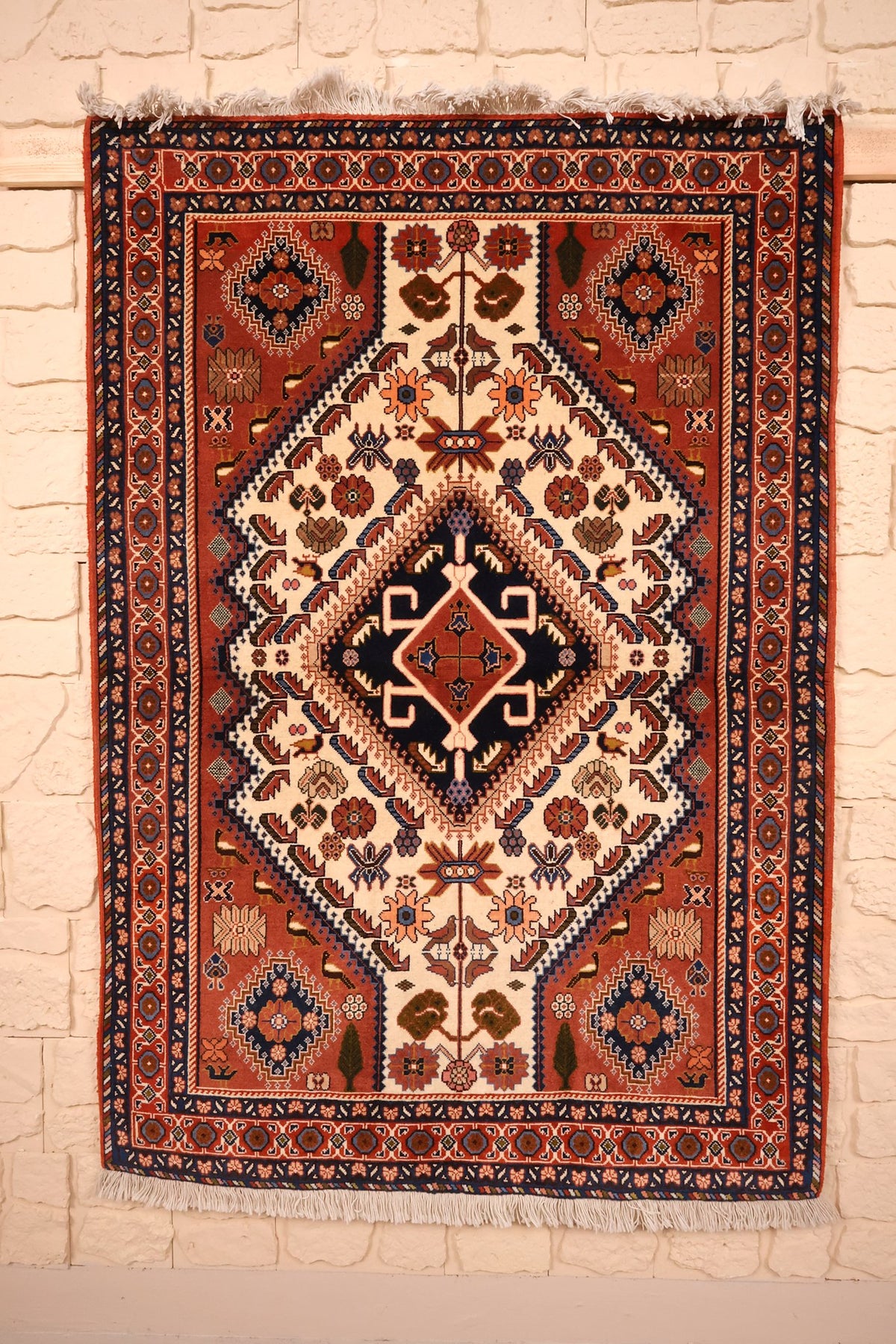 Tapis Heriz rouge 145 × 100 cm, vue d'ensemble du médaillon losangé bleu nuit sur champ ivoire