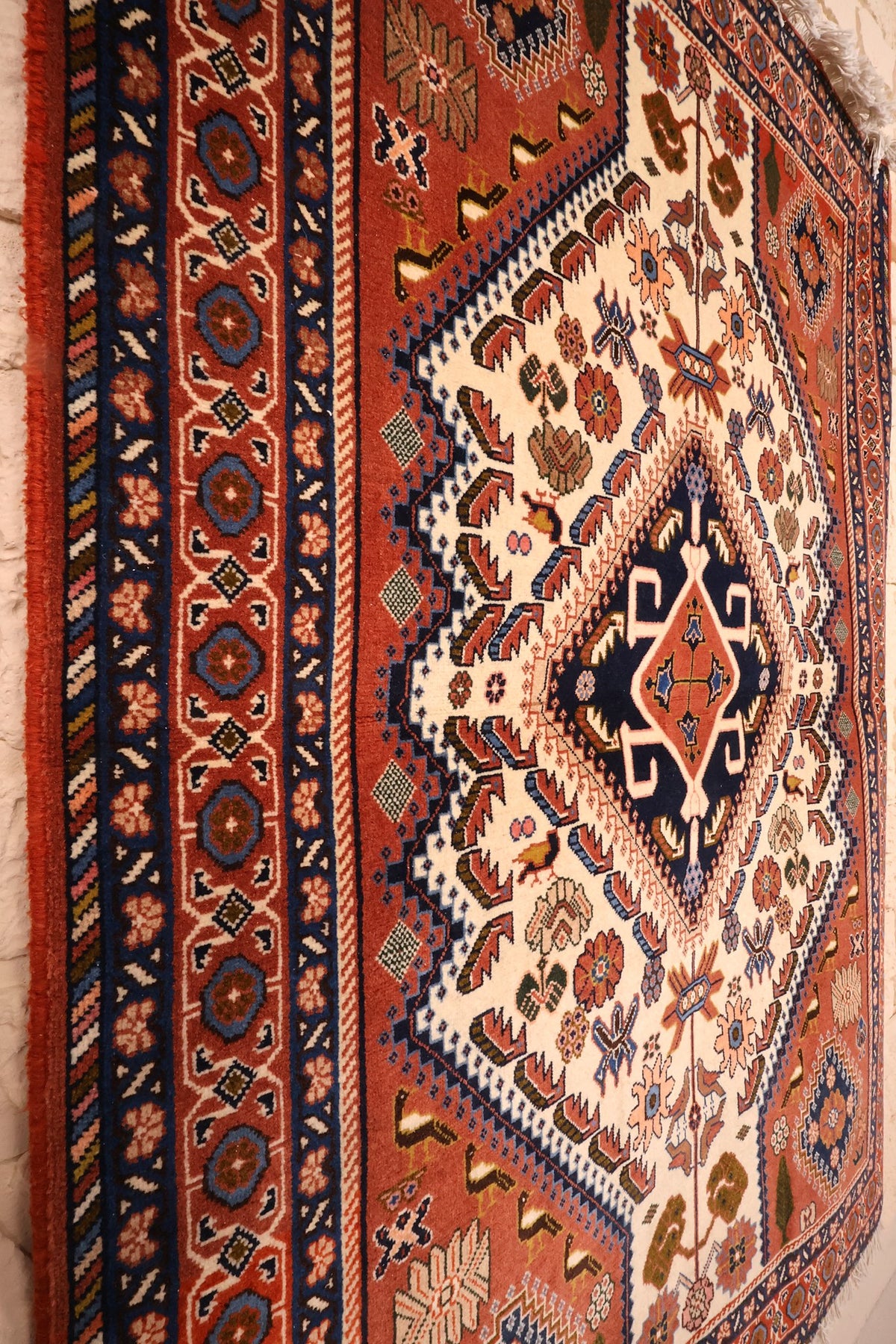 Vue de biais du tapis Heriz rouge : bordure à rosettes et pointe du médaillon central