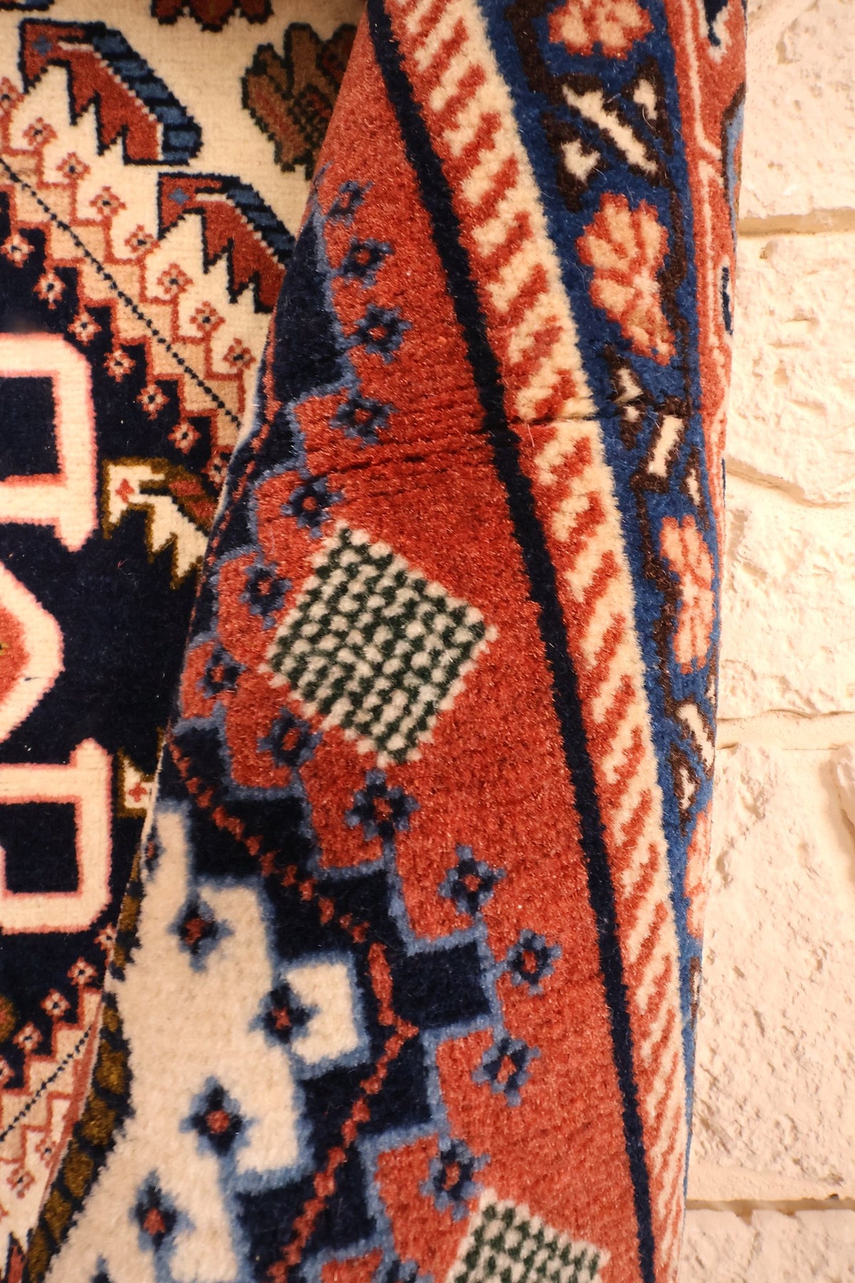 Coin replié du tapis Heriz en laine, écoinçon rouge brique et épaisseur visible