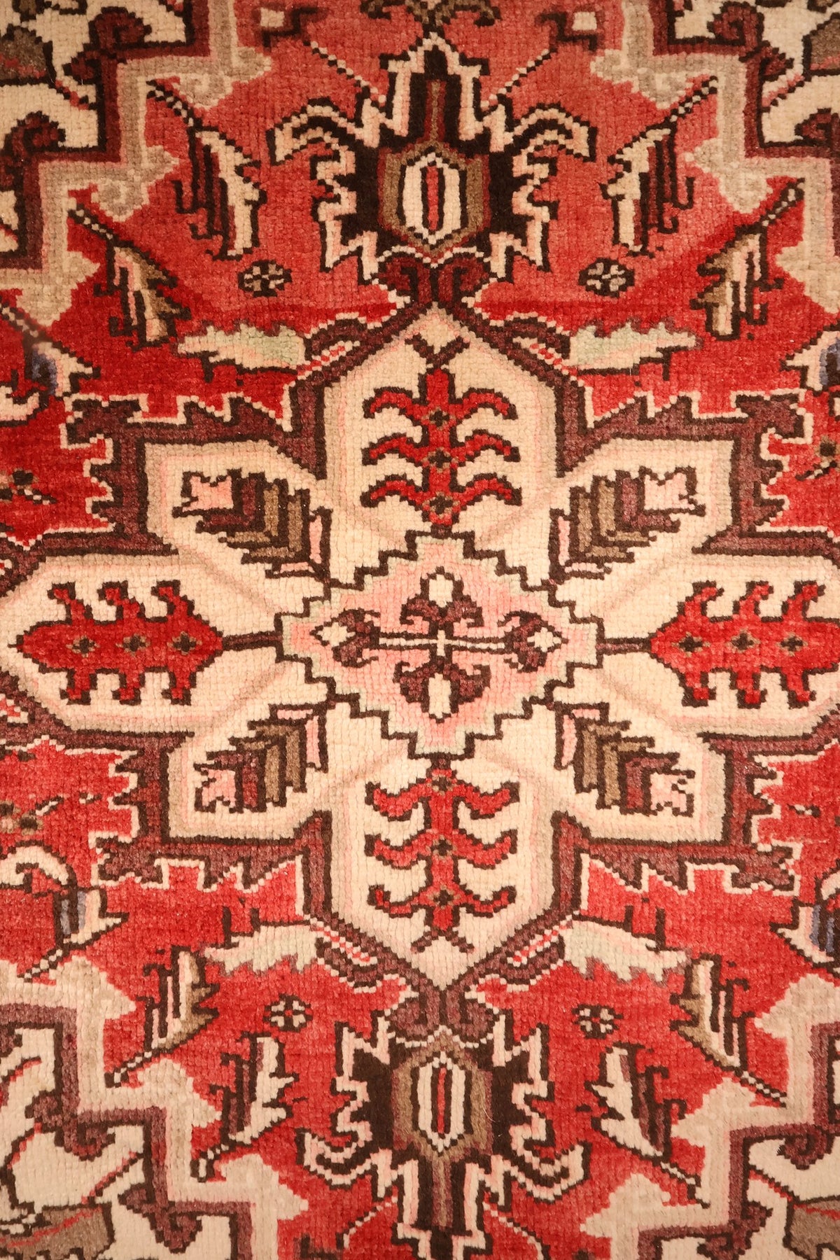 Détail du médaillon anguleux à cœur ivoire et rose du tapis Heriz rouge