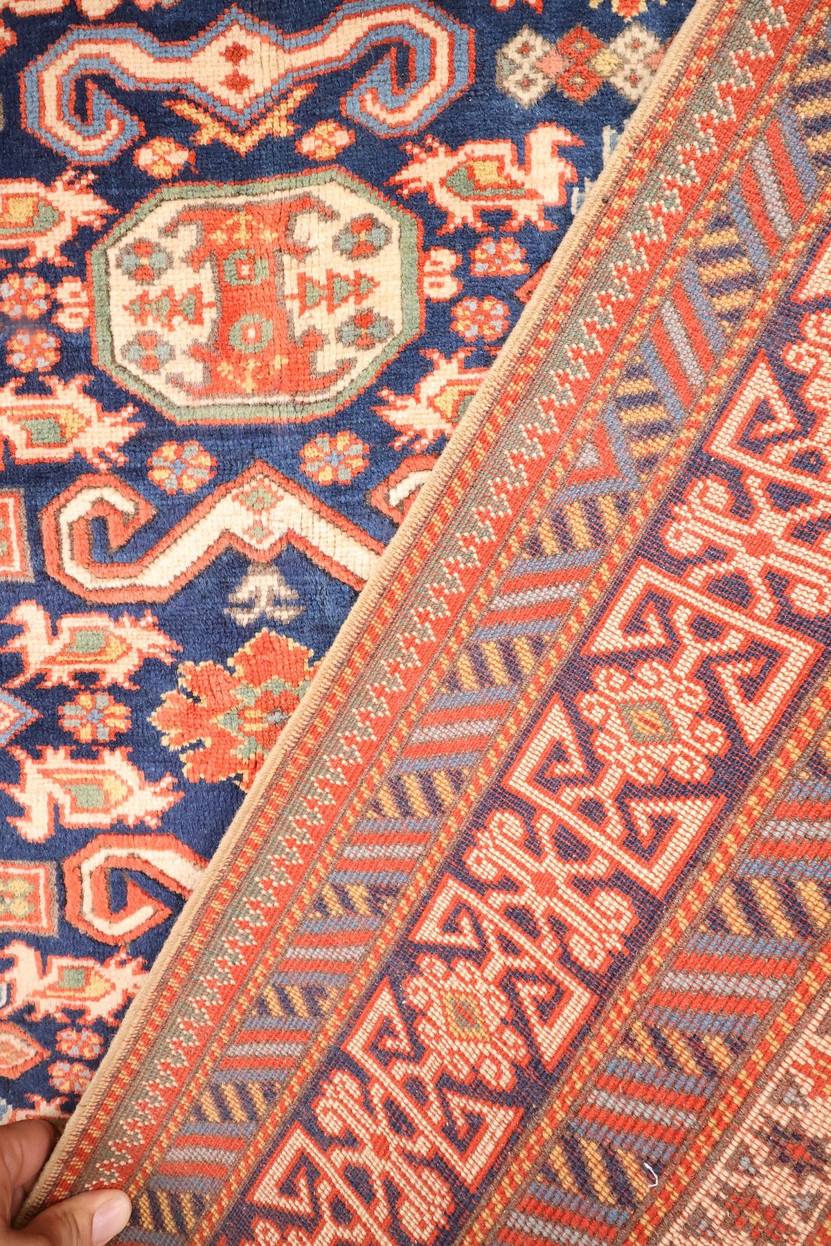Coin replié du tapis Hitit bleu, envers et nœuds visibles près de la bordure