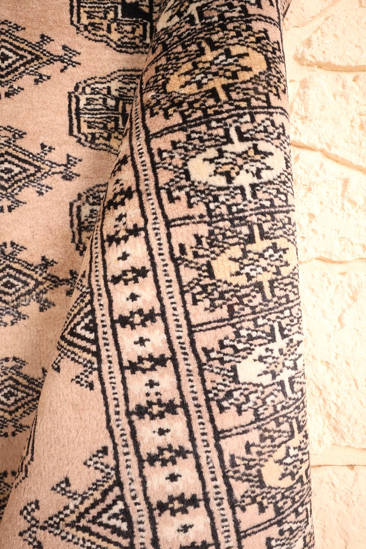 Coin replié du tapis Karachi en laine, bordures géométriques noires et crème