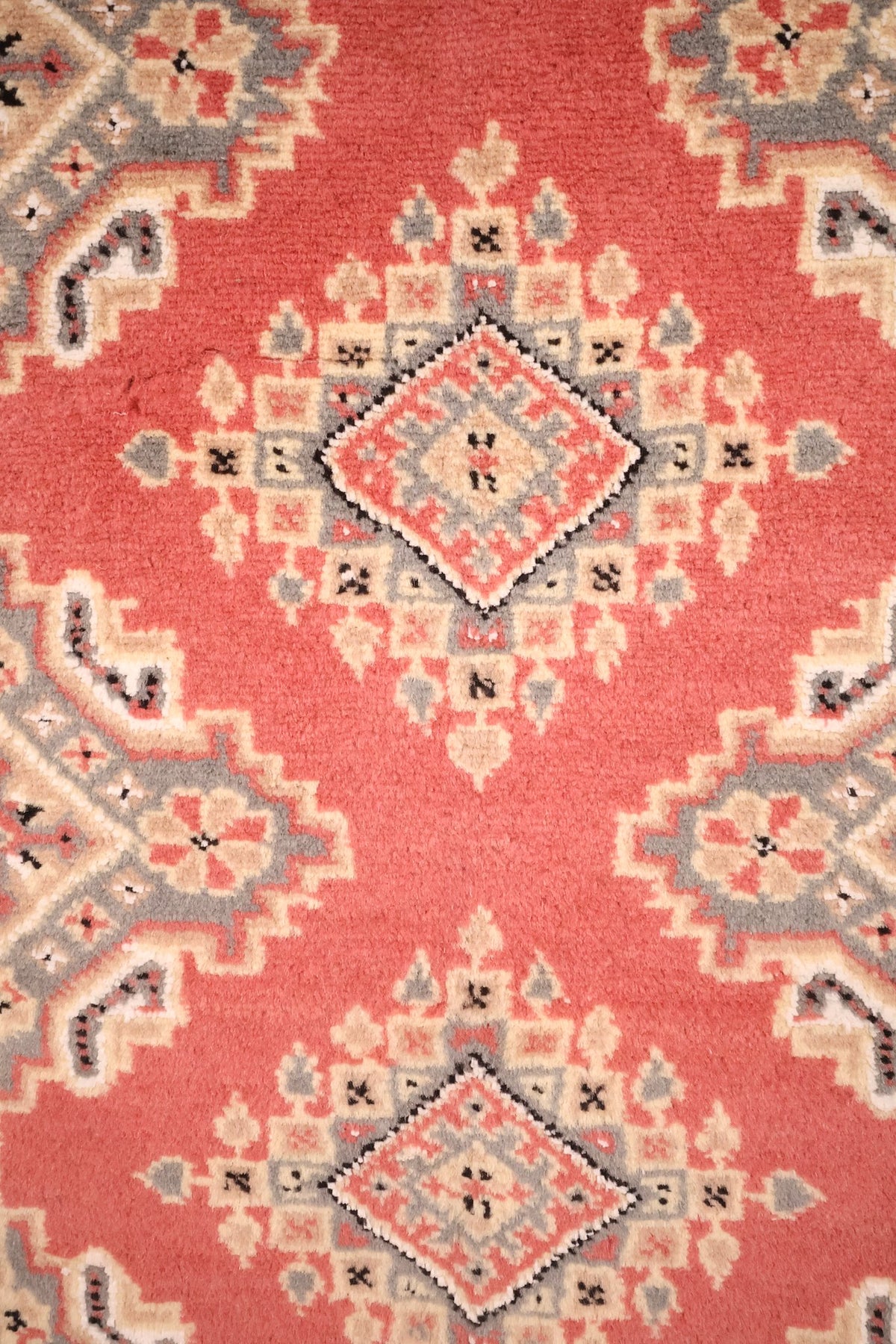 Détail des médaillons crénelés beige et gris sur le champ rose saumon du Karachi