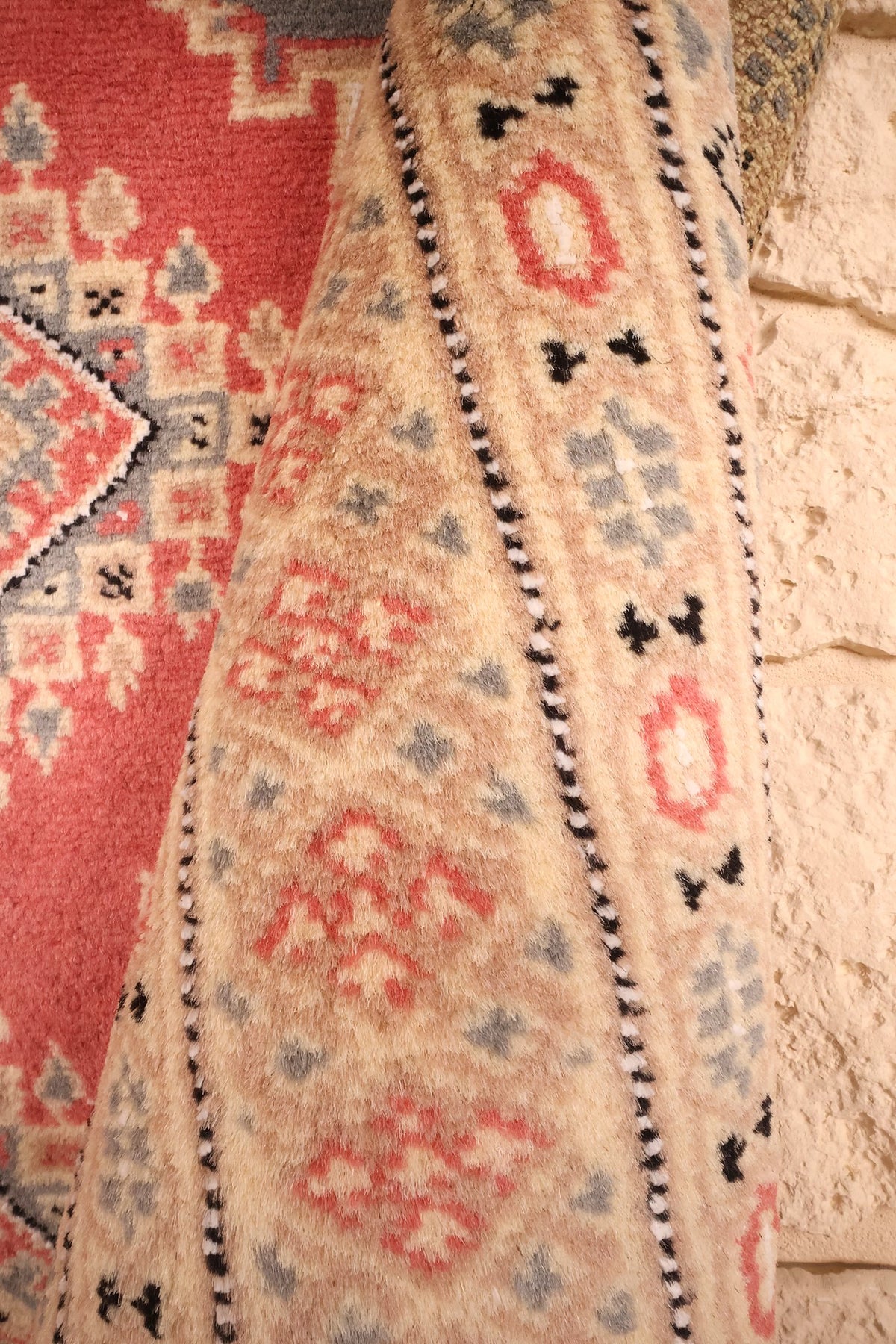Repli de la bordure beige du Karachi en laine, motifs en losange rose et gris