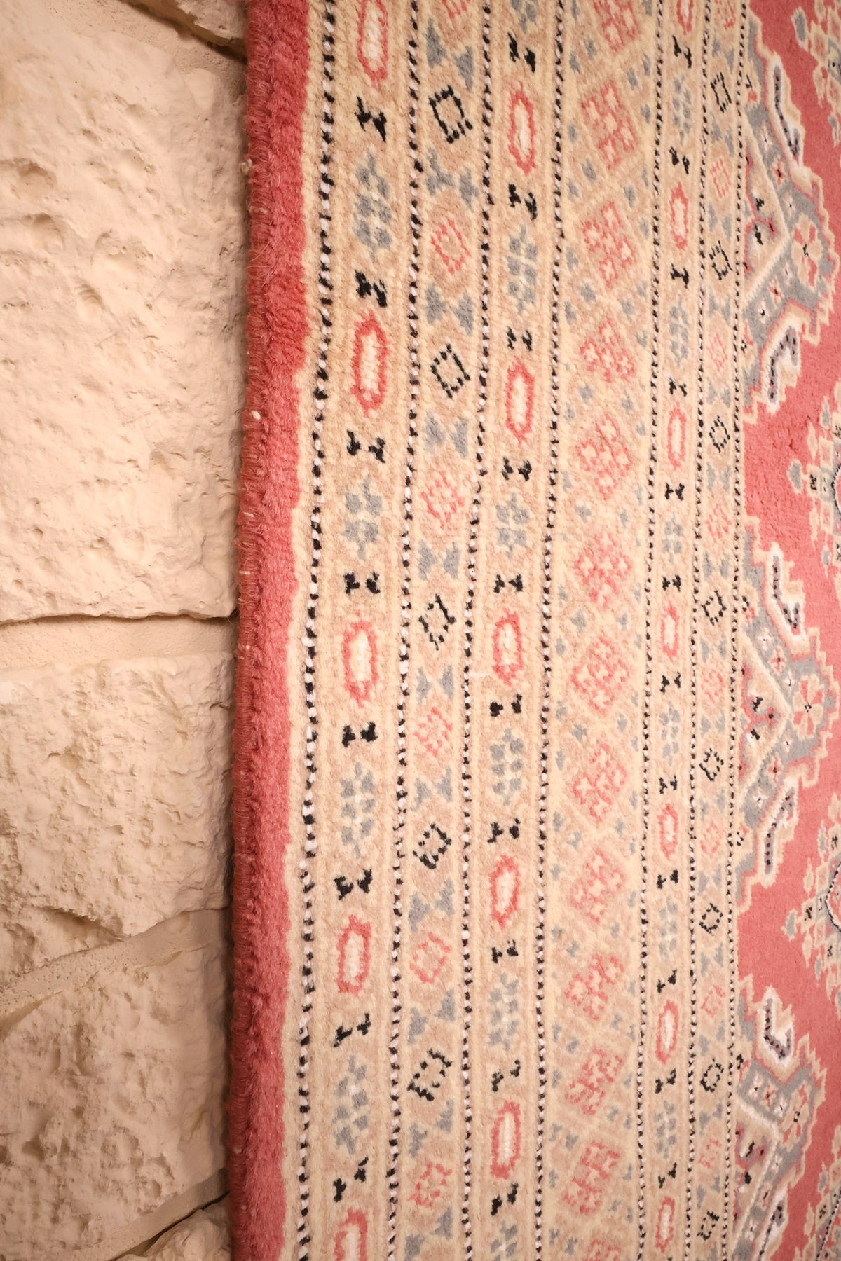 Lisière rose du tapis Karachi longeant les bordures géométriques beige