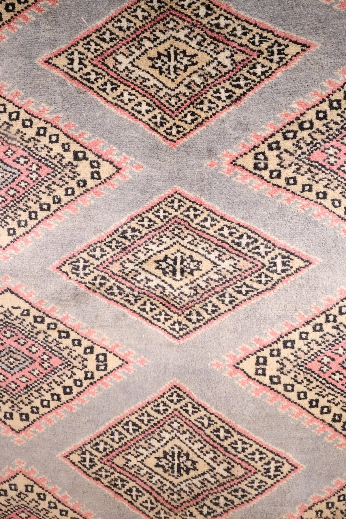 Détail des losanges concentriques beige, rose et noir sur champ gris clair
