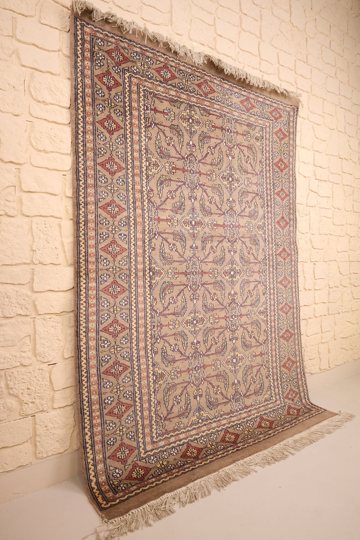 Tapis Karachi beige dressé de biais, franges écrues et bordures multiples visibles
