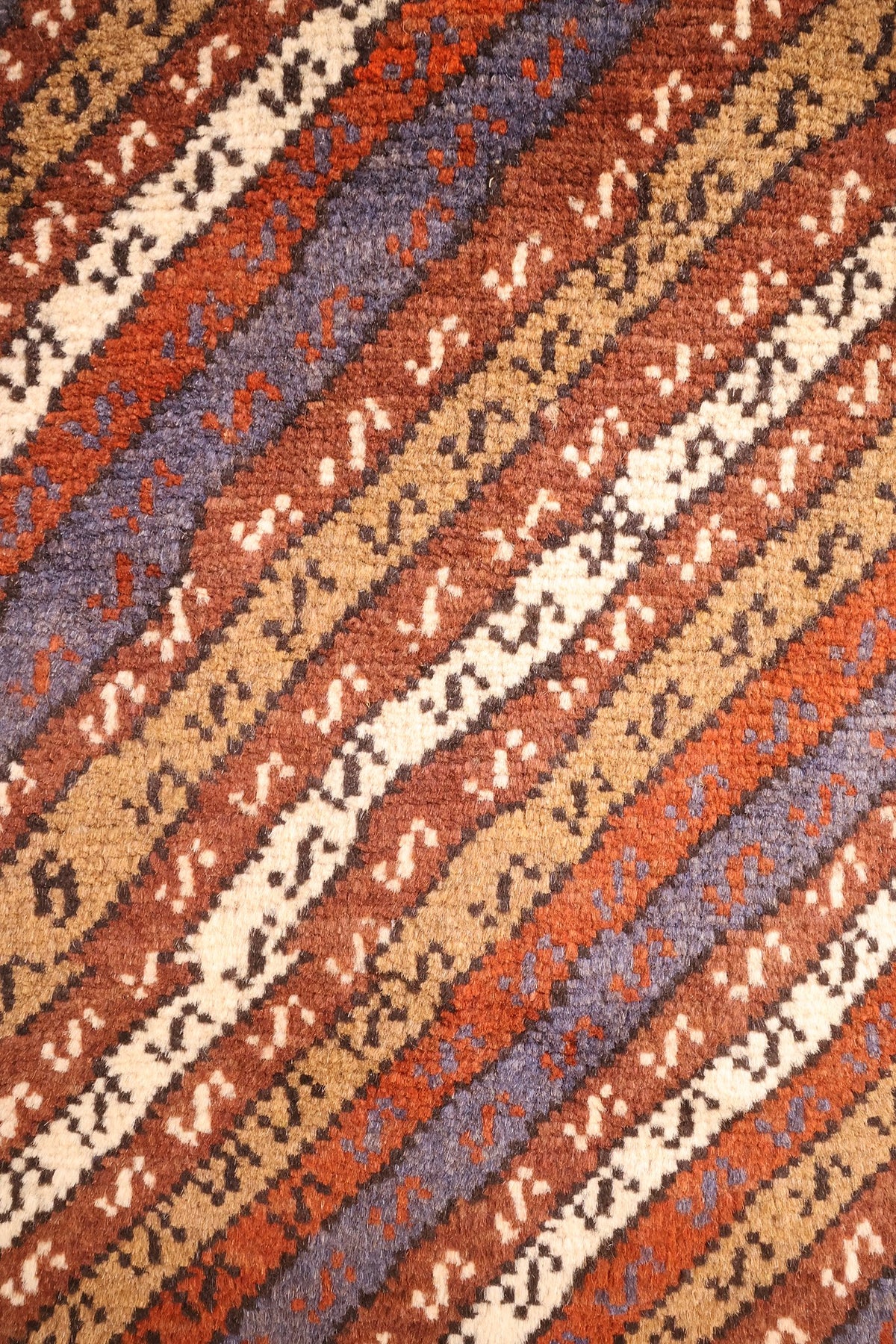 Détail des bandes diagonales beige, rouille et bleu-gris semées de petits crochets