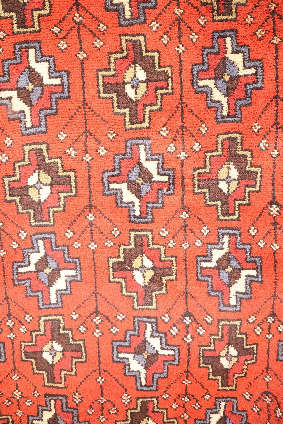 Détail du champ rouge orangé : motifs cruciformes à cœur ivoire, brun et bleu-gris