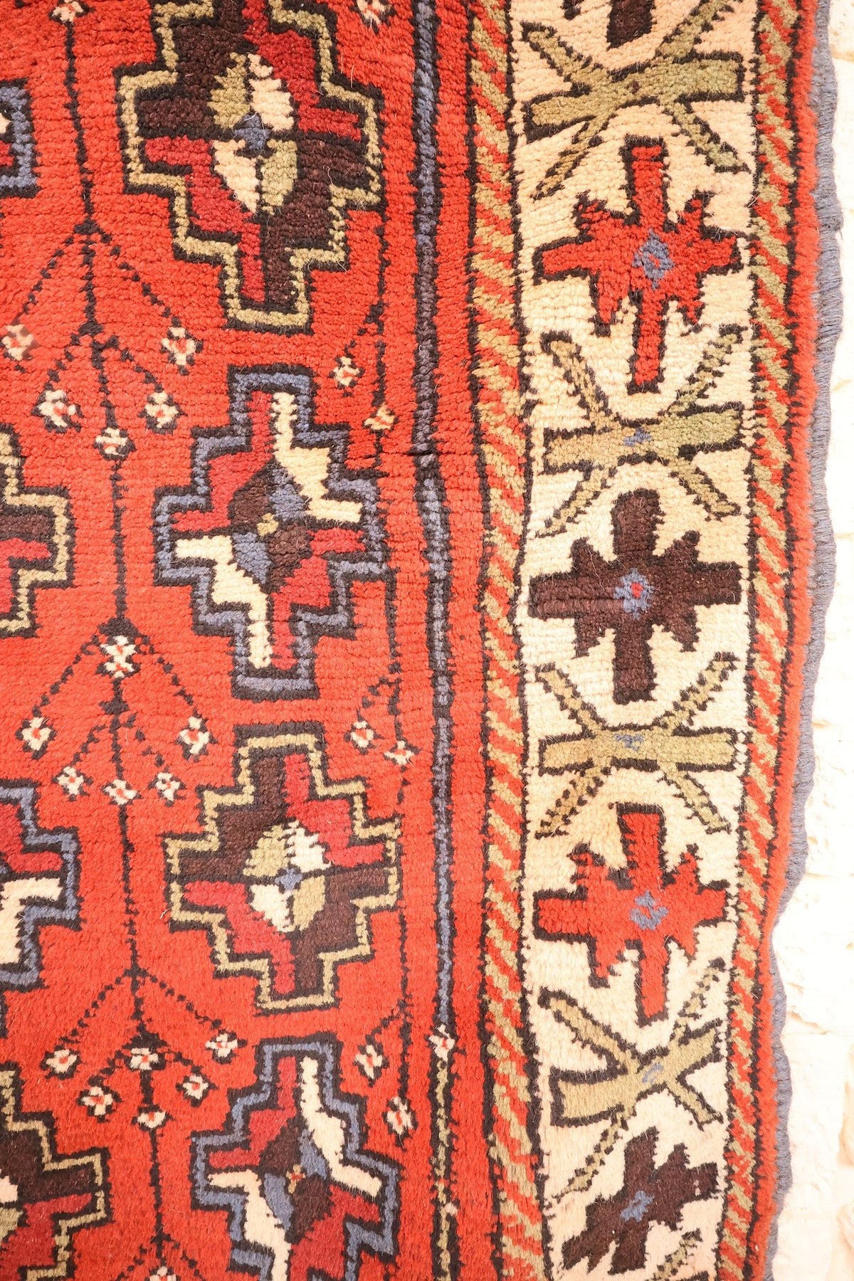 Bordure ivoire du tapis Karachi, croix brunes et rouges et filets rayés