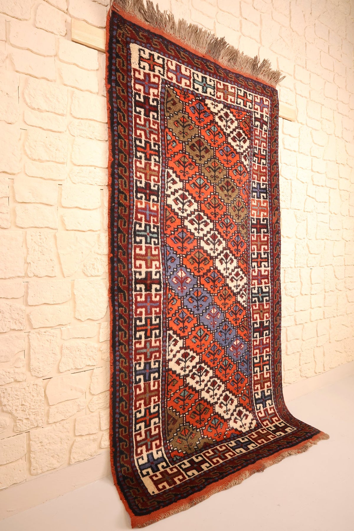 Tapis Pakistan orange et bleu vu de biais, champ répétitif sans médaillon central