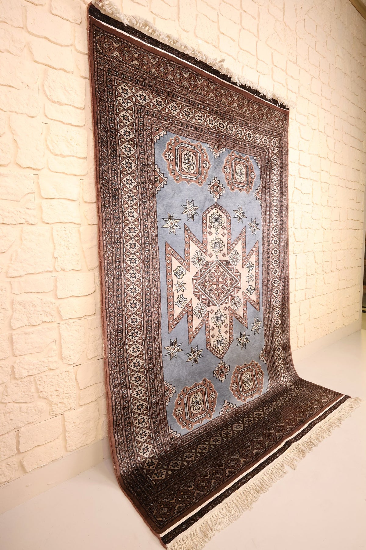 Tapis Karachi gris et brun vu de biais, bordures à losanges crénelés