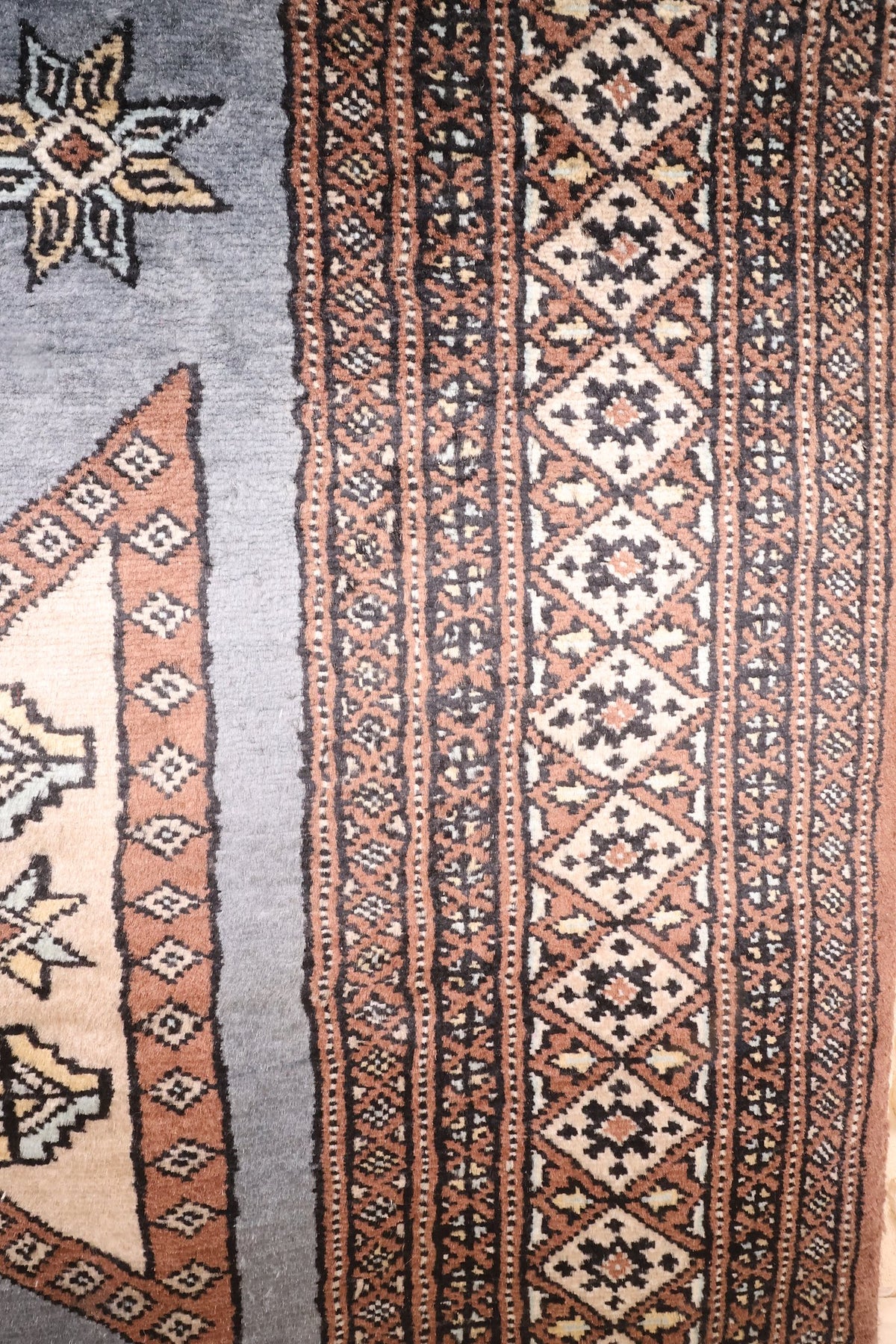 Bordures brunes et beiges à losanges crénelés et fines rayures, tapis Karachi