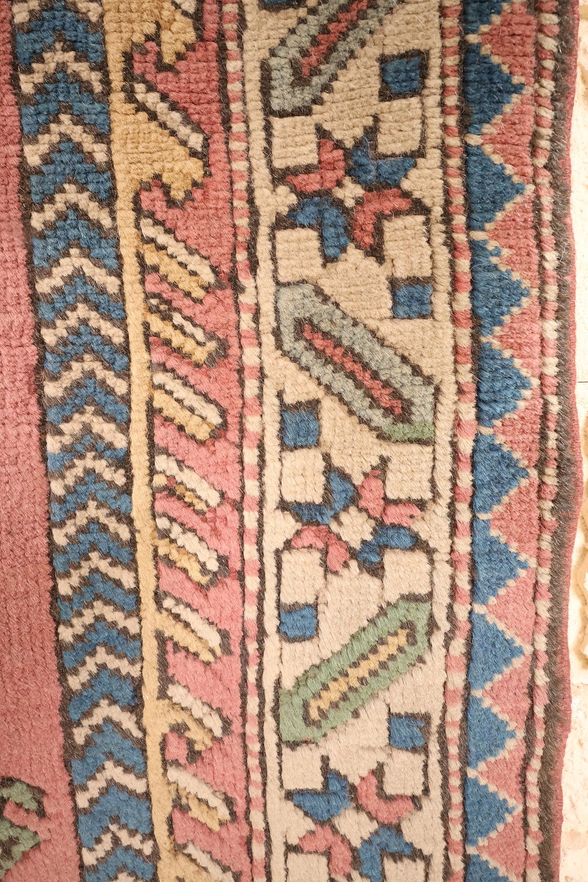 Bordure ivoire à étoiles et galons en chevrons du tapis Kars rose
