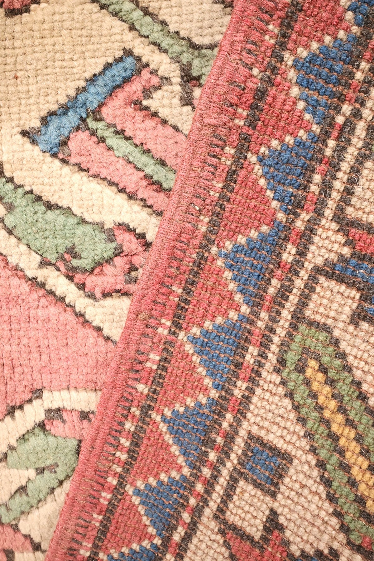 Coin replié du tapis Kars, nœuds et triangles bleus visibles à l'envers