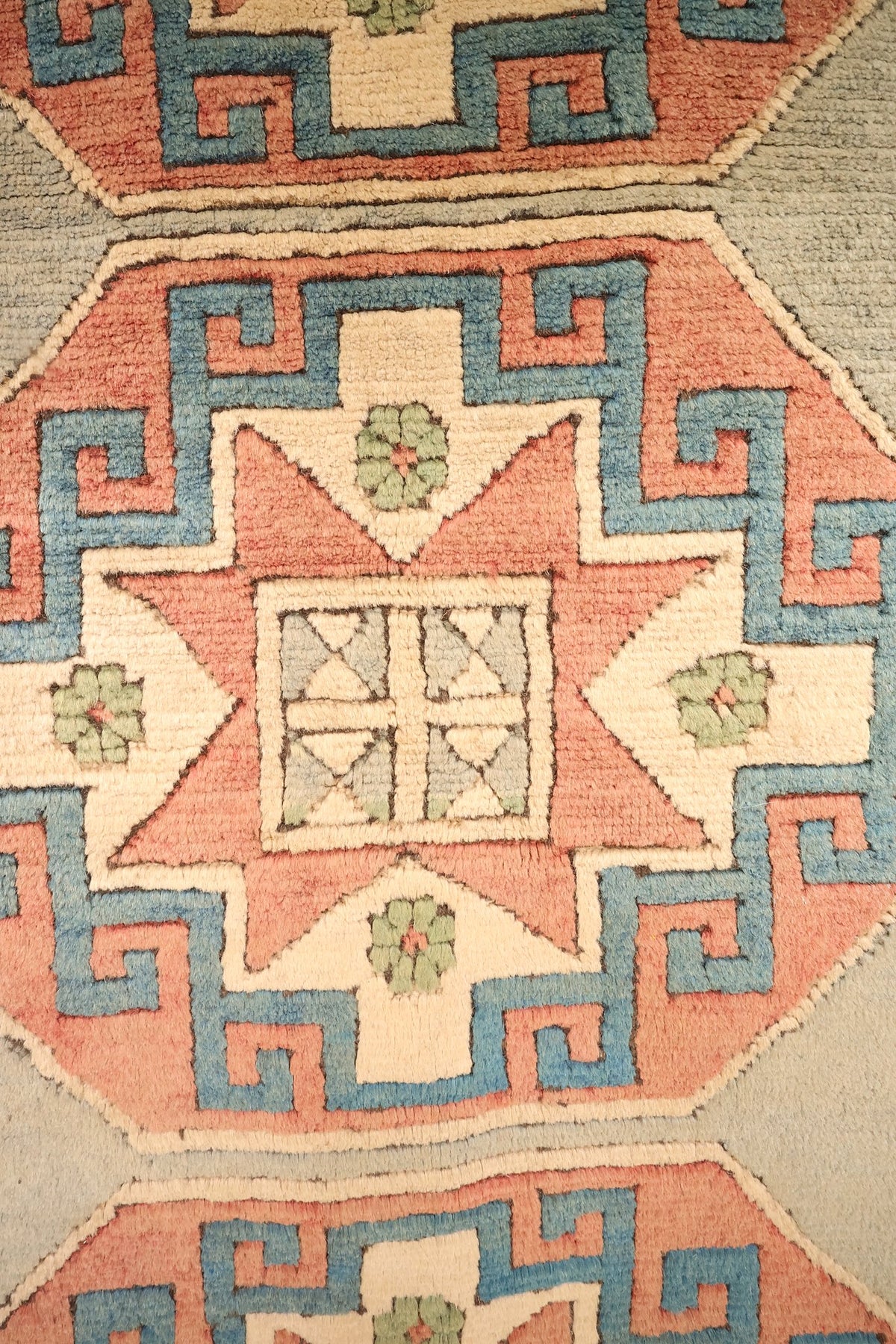 Détail d'un médaillon octogonal à étoile rose et crochets bleus du tapis Kars