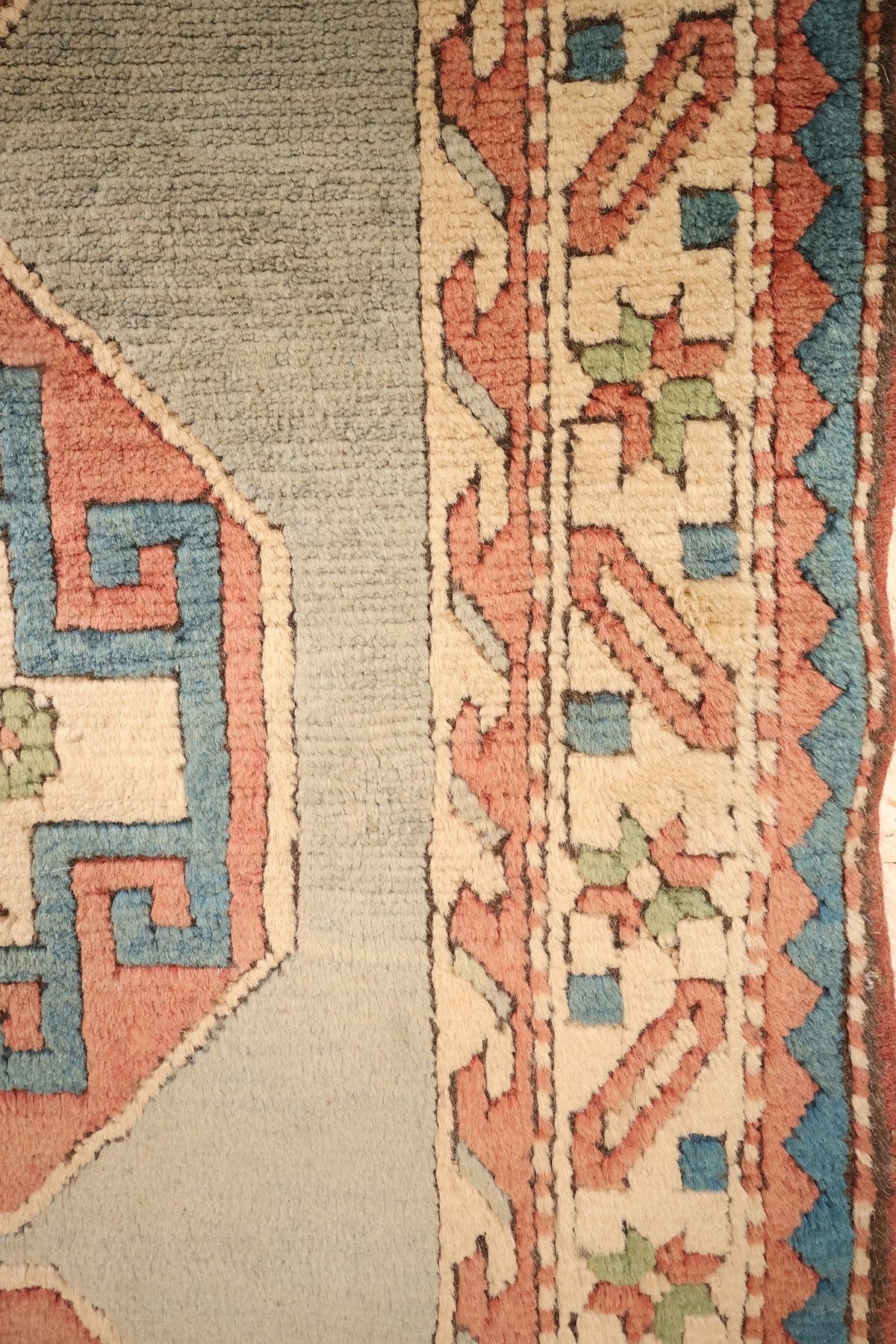 Bordure ivoire à rinceaux rose et bleu du tapis Kars, le long du champ bleu-gris