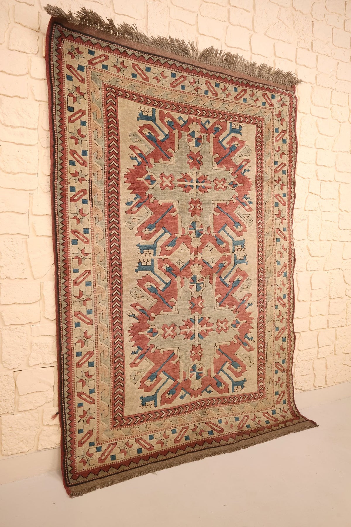 Tapis Kars en laine vu de biais, trois médaillons étoilés sur champ beige-gris