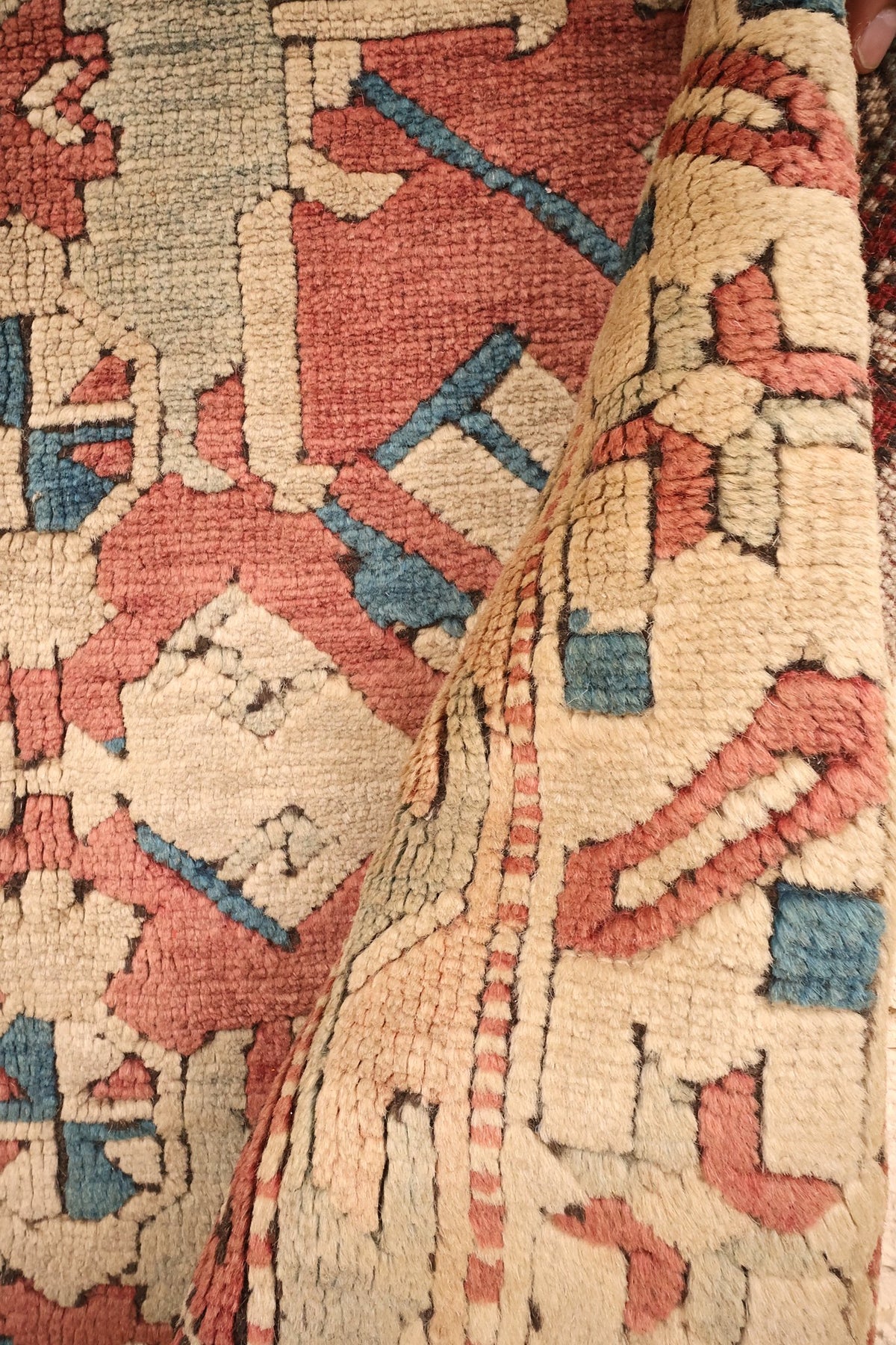 Coin replié du tapis Kars, bordure claire à motifs obliques et laine nouée