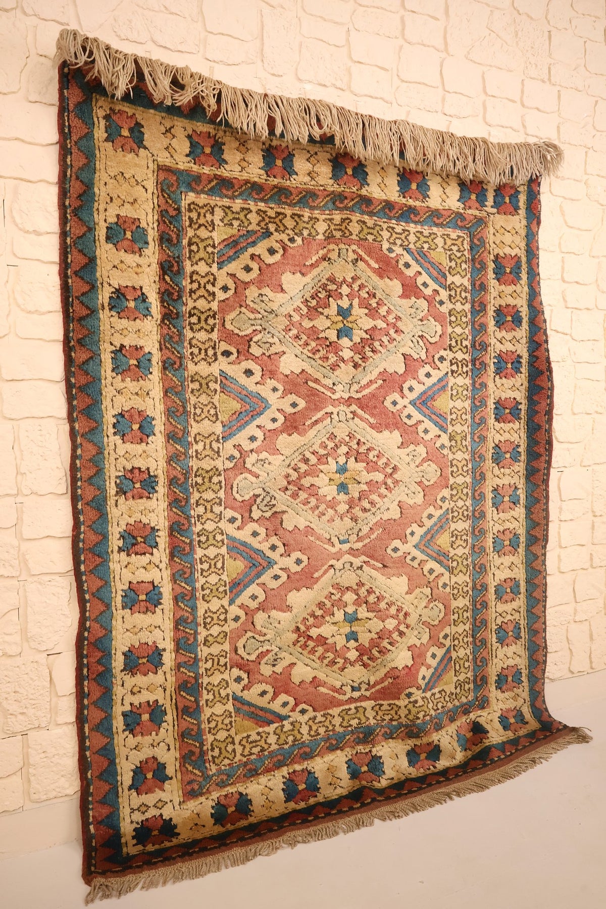 Tapis Kars rectangulaire rose et beige vu de biais, franges beiges visibles