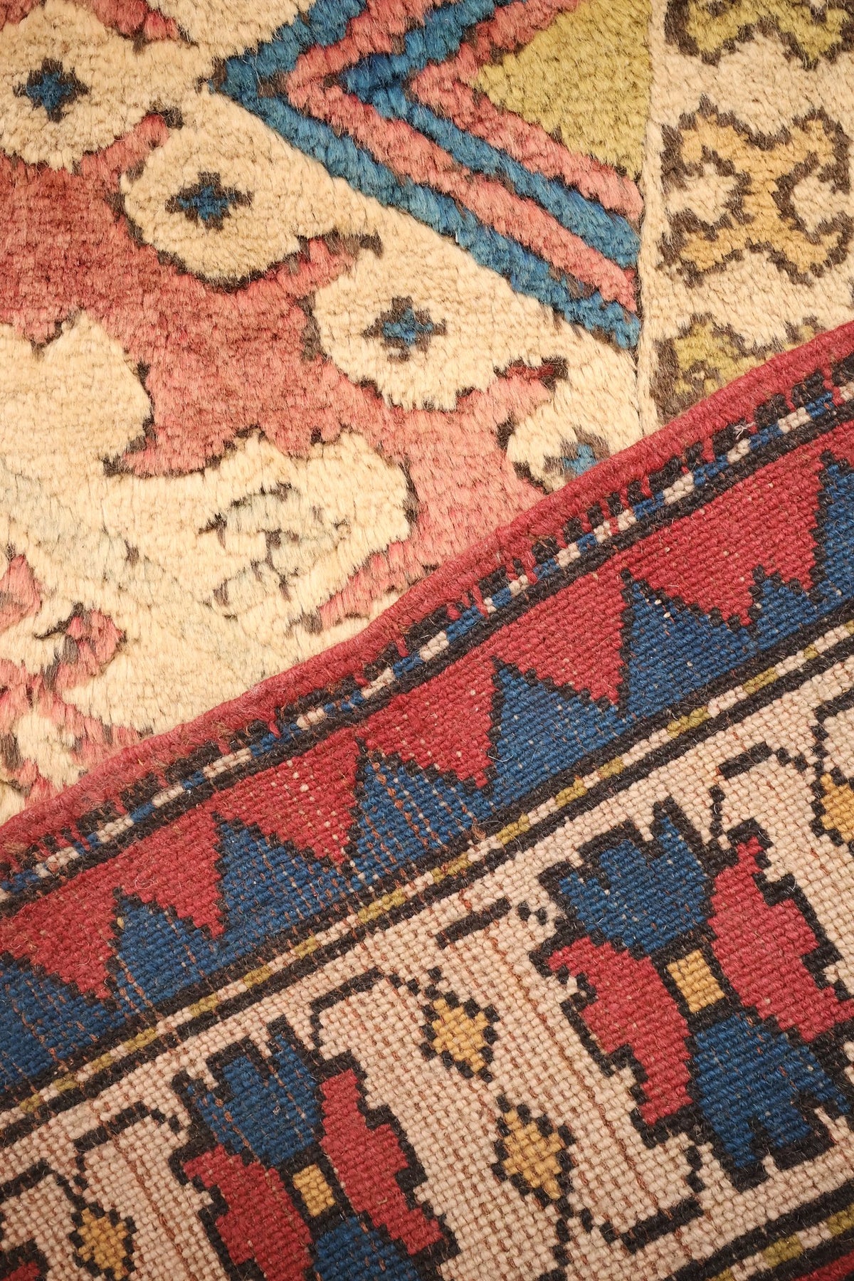 Coin replié du tapis Kars, envers et nœuds visibles sous la bordure