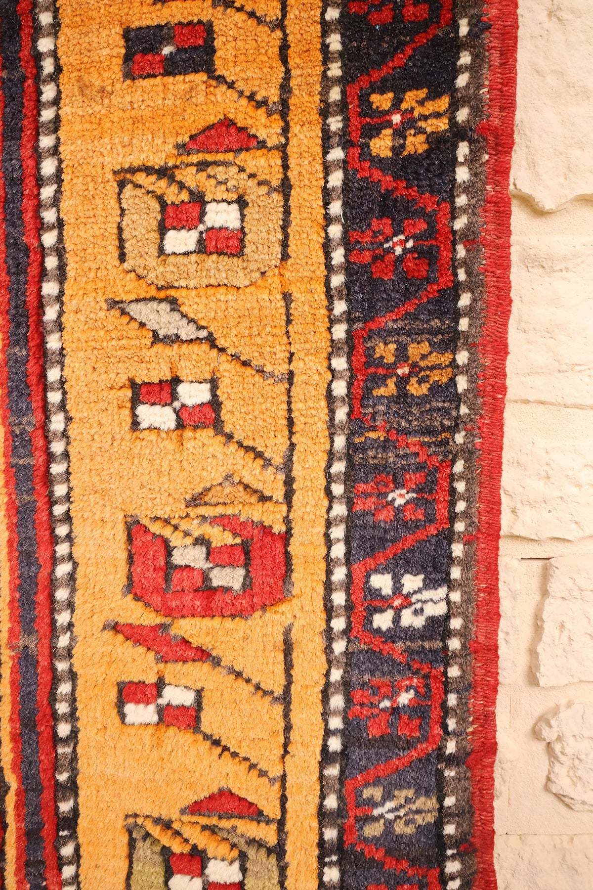 Bordure jaune orangé à motifs crénelés rouge et blanc du tapis Kars