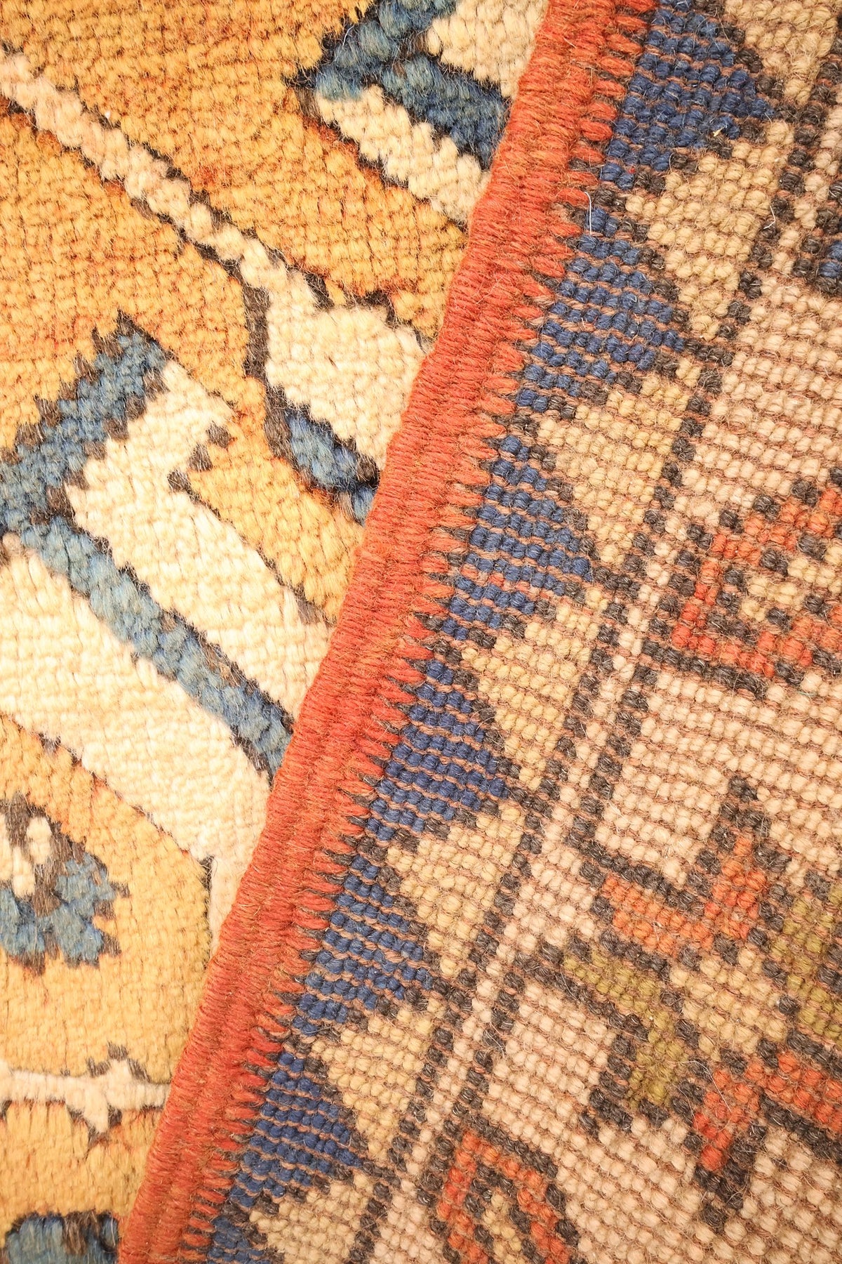 Envers du tapis Kars, nœuds et bordure bleue visibles au repli