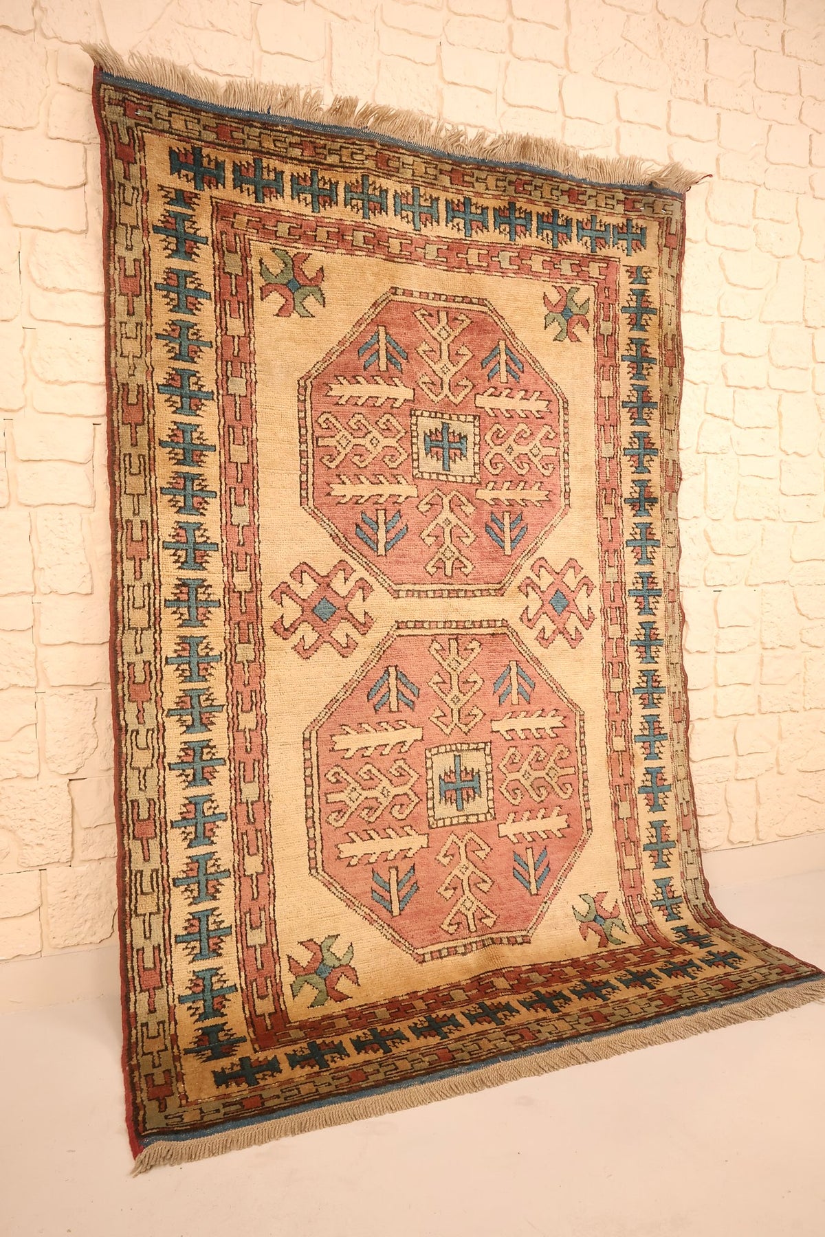 Vue de biais du tapis Kars beige et rose, bordures bleues et franges visibles
