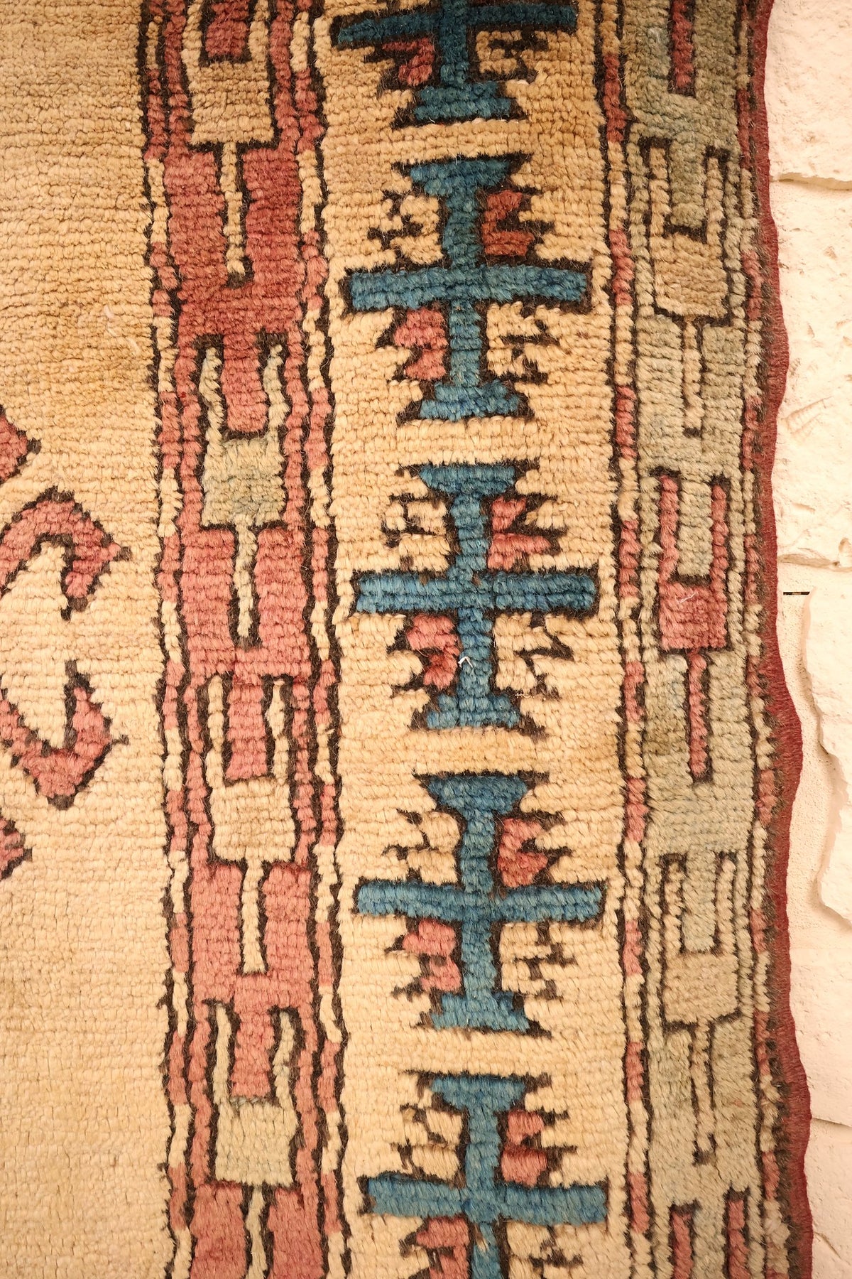 Bordure ivoire à motifs cruciformes bleus et galon rose du tapis Kars beige