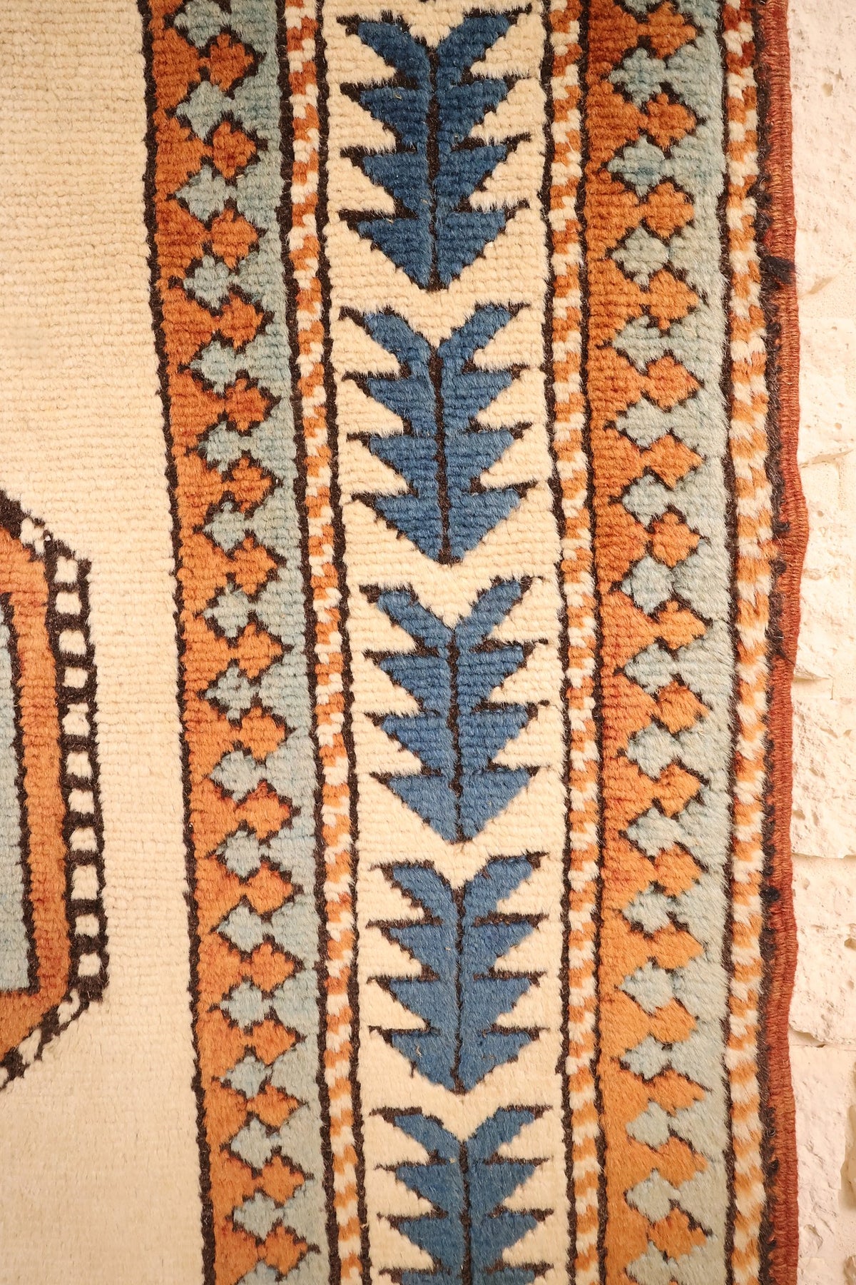 Bordure ivoire du tapis Kars, arbres stylisés bleus et bandes à losanges orange
