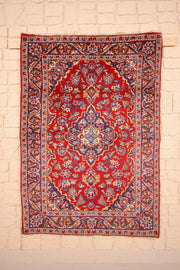 Tapis Kashan rouge 150 × 104 cm, vue d'ensemble du médaillon bleu-violet et des rinceaux fleuris