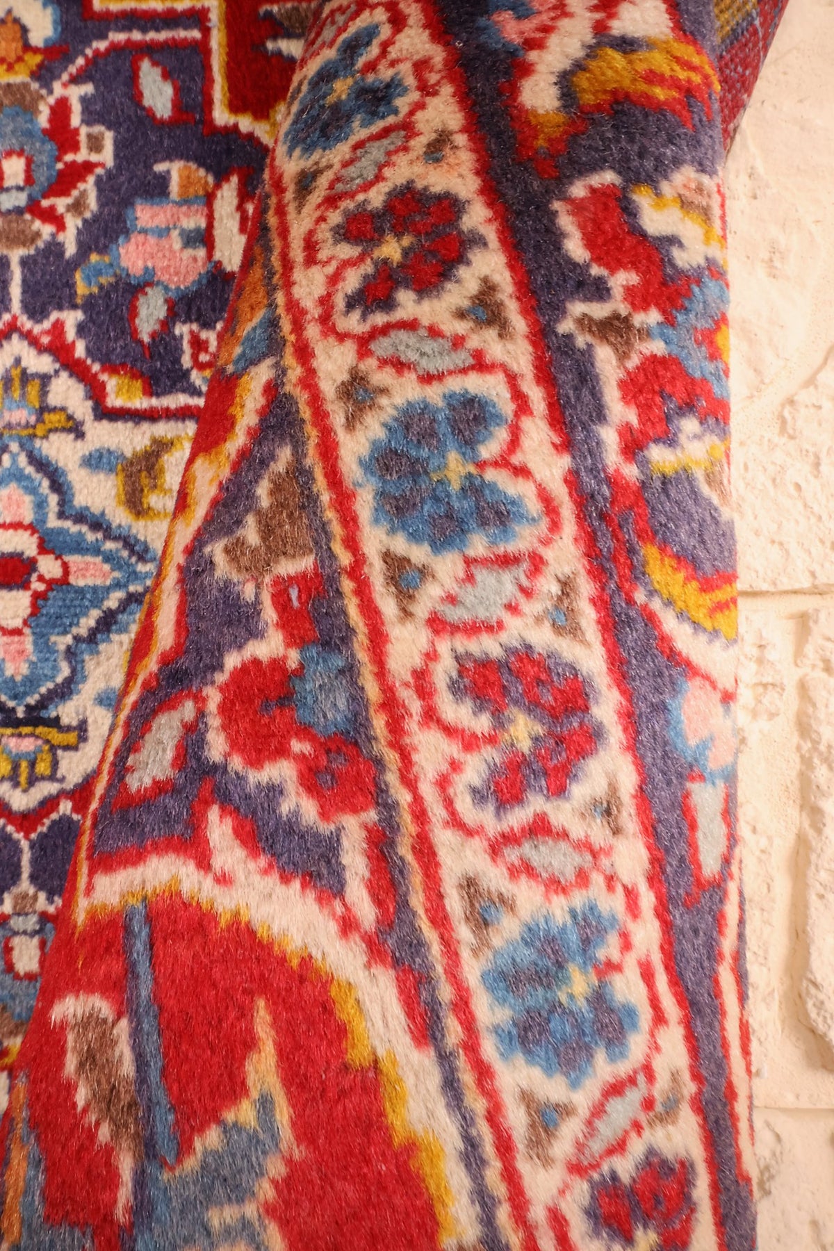 Coin replié du tapis Kashan rouge, épaisseur et contre-bordure ivoire fleurie