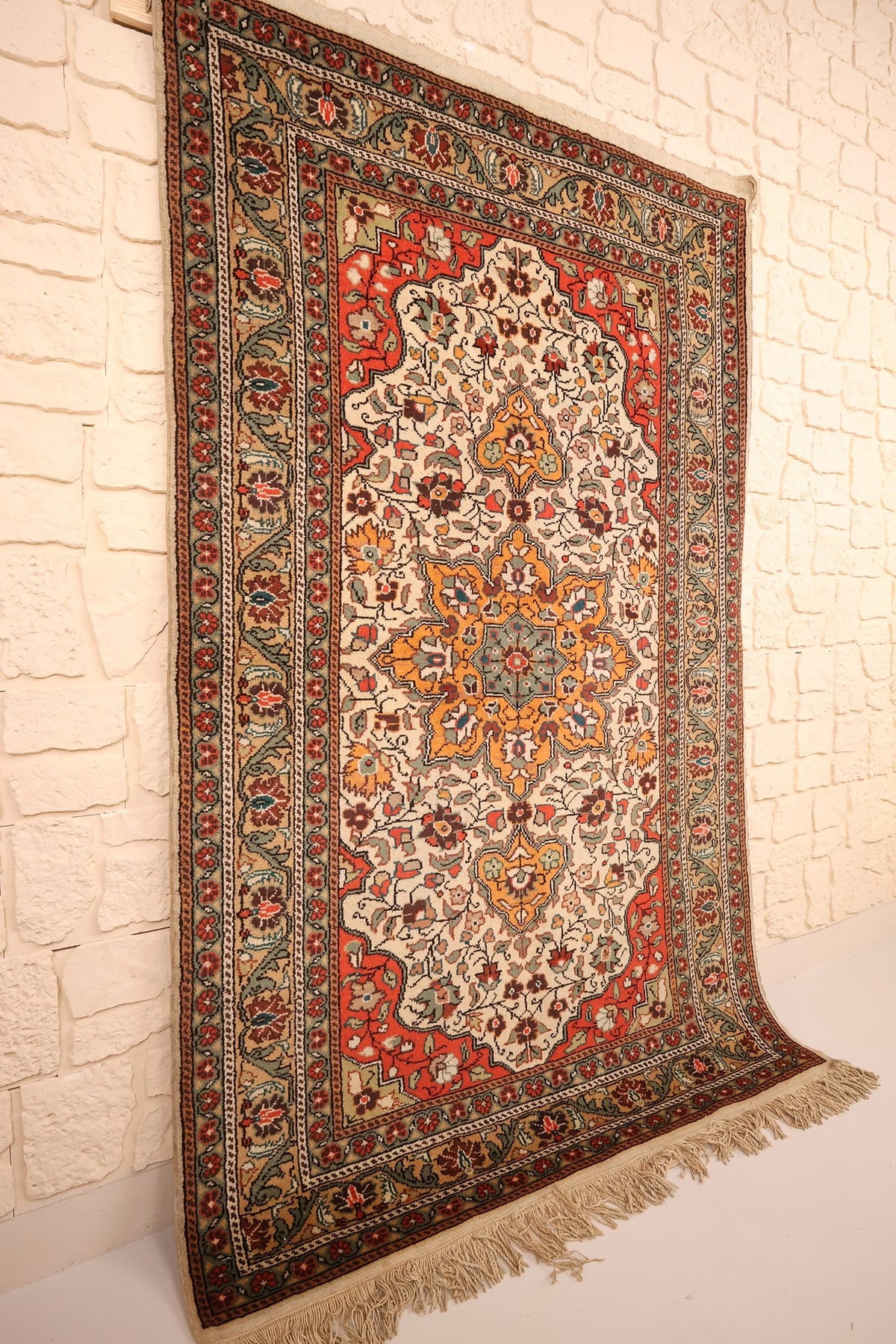 Tapis Kayseri en laine vu de biais, médaillon étoilé orange et écoinçons rouges