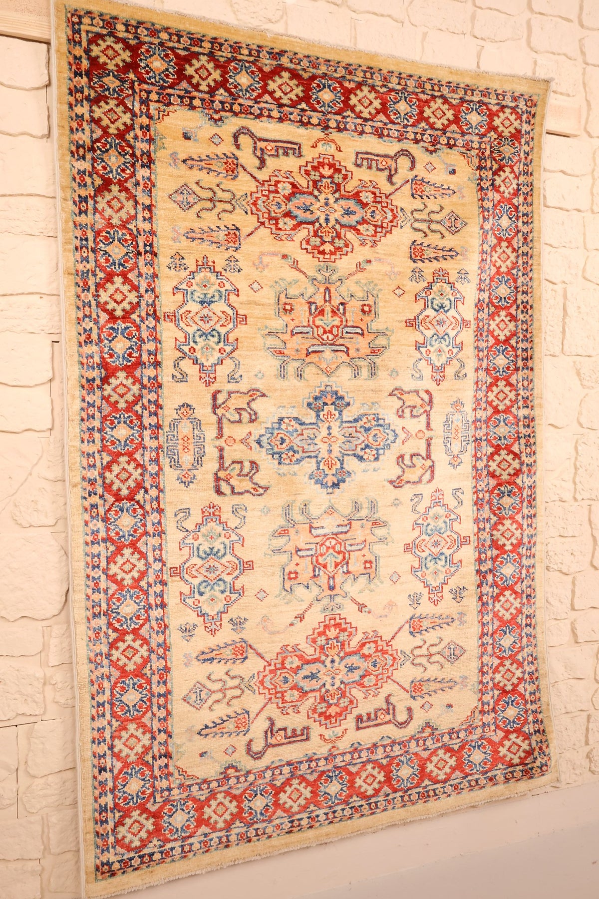 Tapis Kazak beige et rouge en laine, vue de biais sur le champ et les bordures