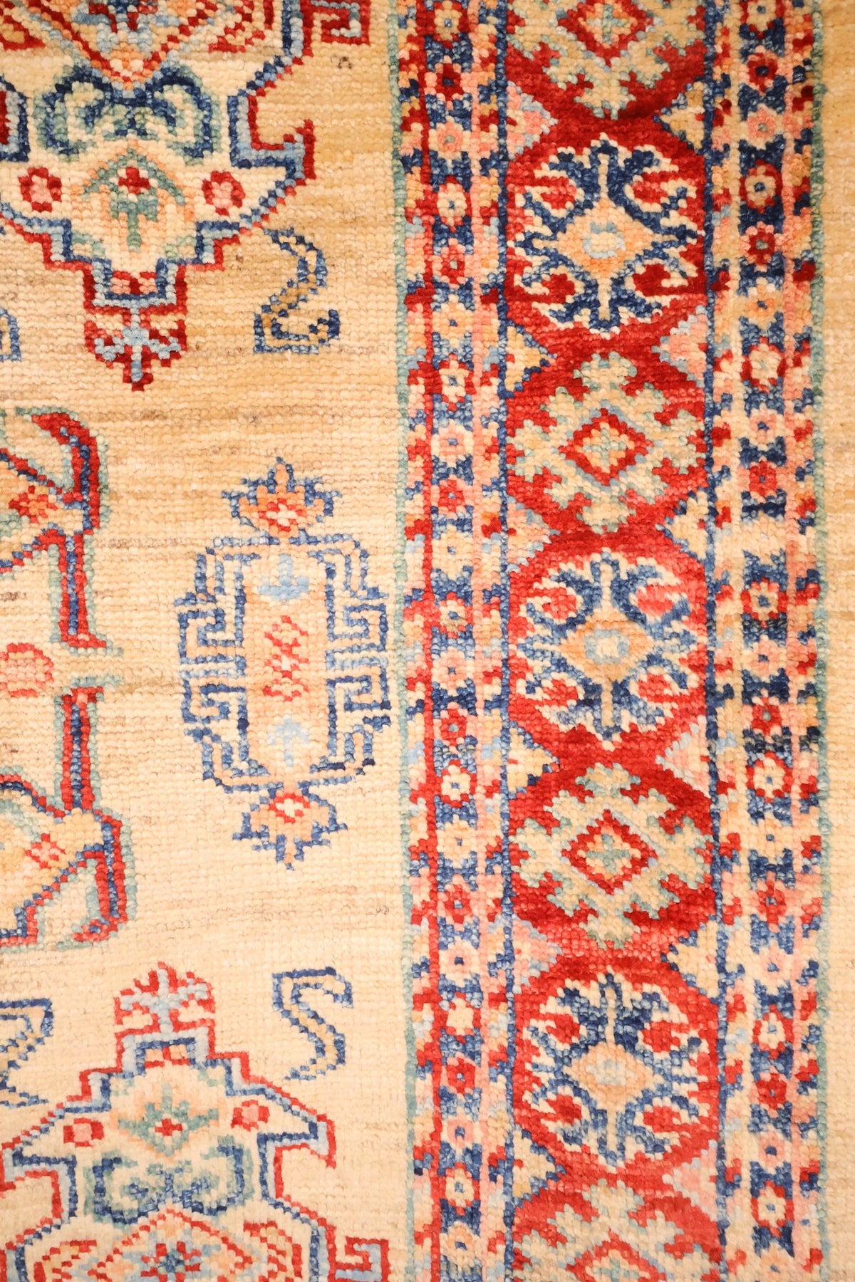 Bordure rouge à rosettes géométriques et contre-bordures bleues du tapis Kazak
