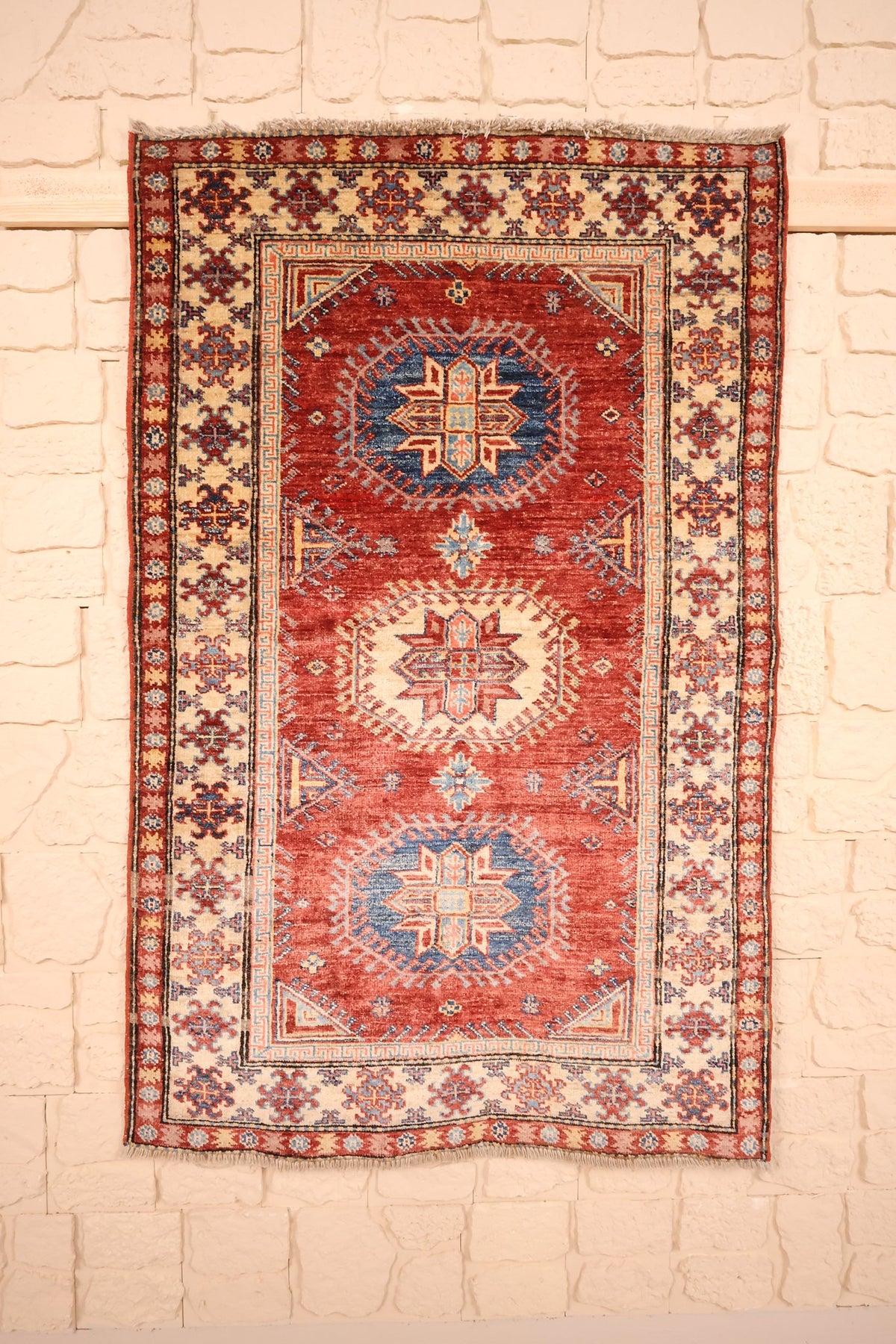 Tapis Kazak rouge 138 × 89 cm, vue d'ensemble aux trois médaillons crantés