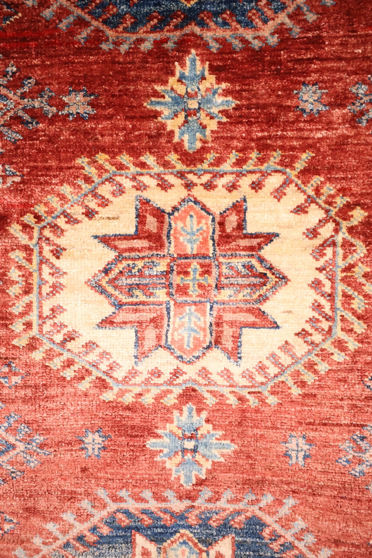 Détail du médaillon étoilé ivoire et des rosettes bleues du tapis Kazak