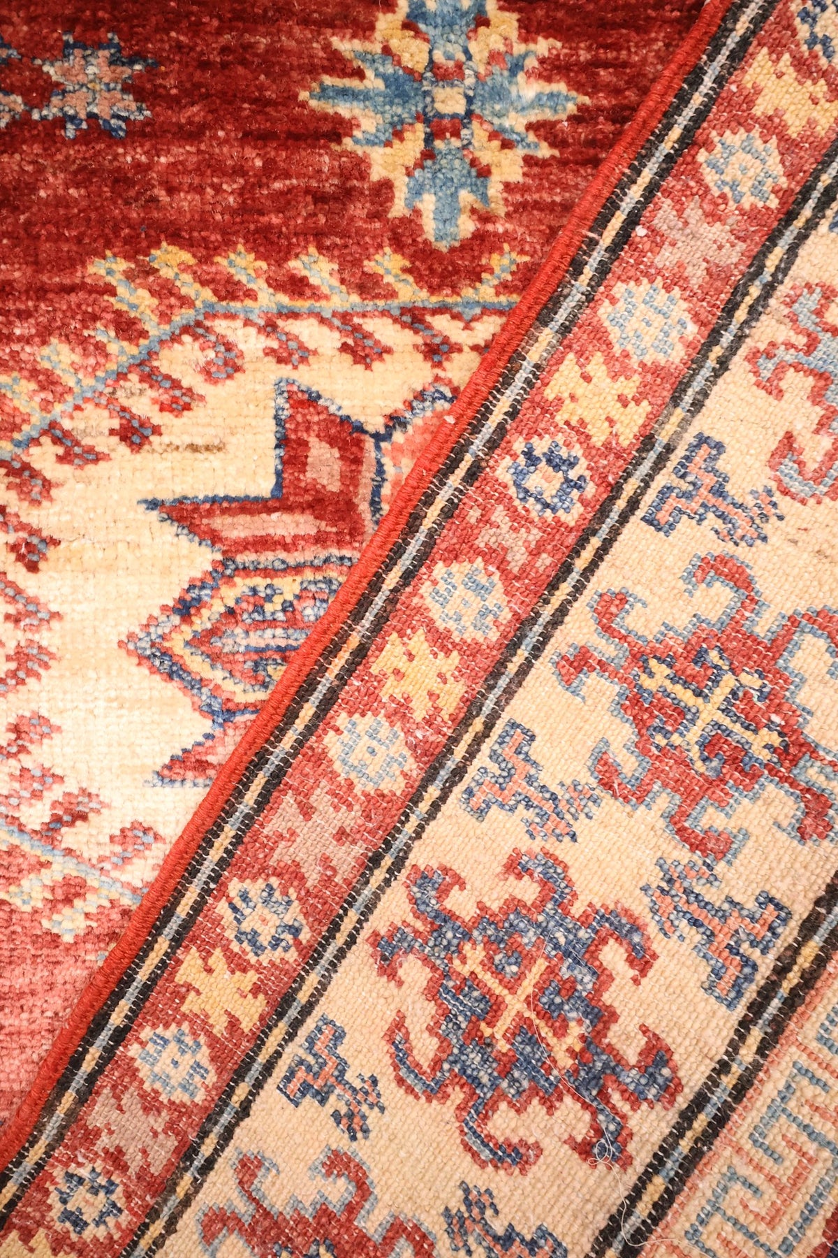 Coin du tapis Kazak noué à la main, écoinçon cranté et filets rouges
