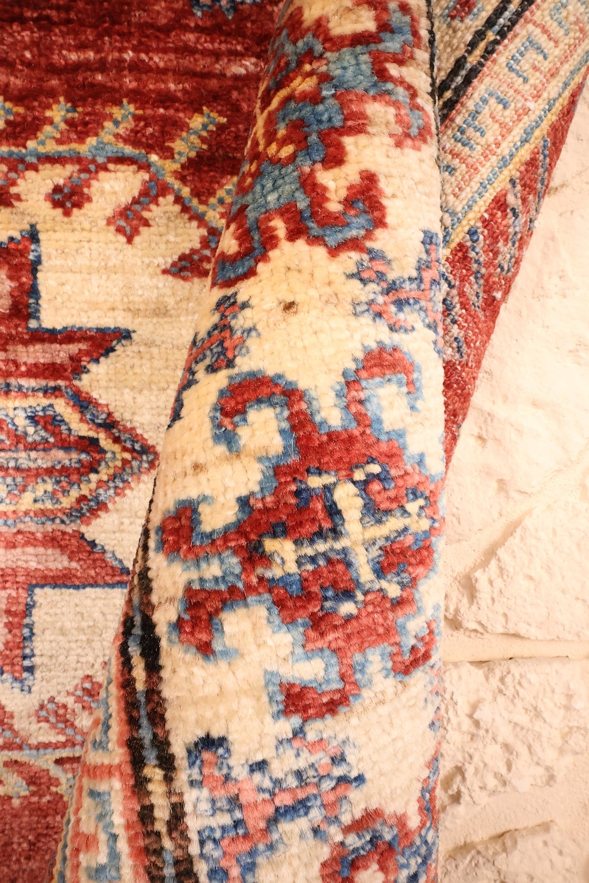 Coin replié du tapis Kazak en laine, bordure ivoire et bleue en relief