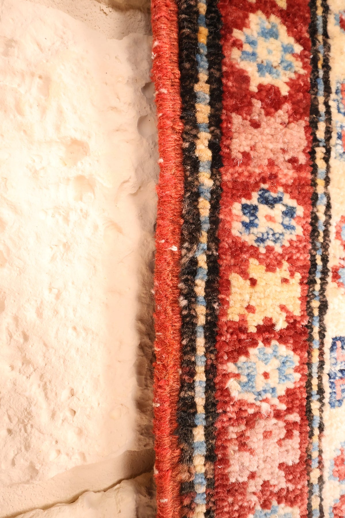 Lisière rouge du tapis Kazak, filets et rosettes de la bande extérieure