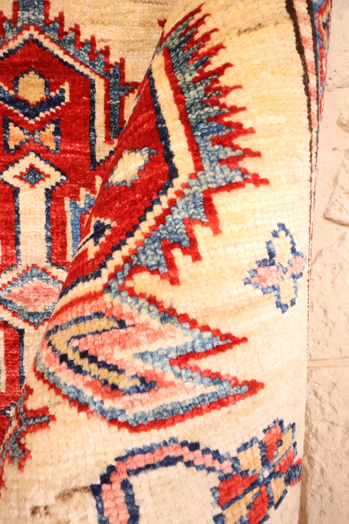 Pli de la laine du tapis Kazak, médaillon rouge et dents bleues en gros plan