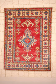 Tapis Kazak rouge 142 × 108 cm, vue d'ensemble avec médaillon étoilé bleu et ivoire
