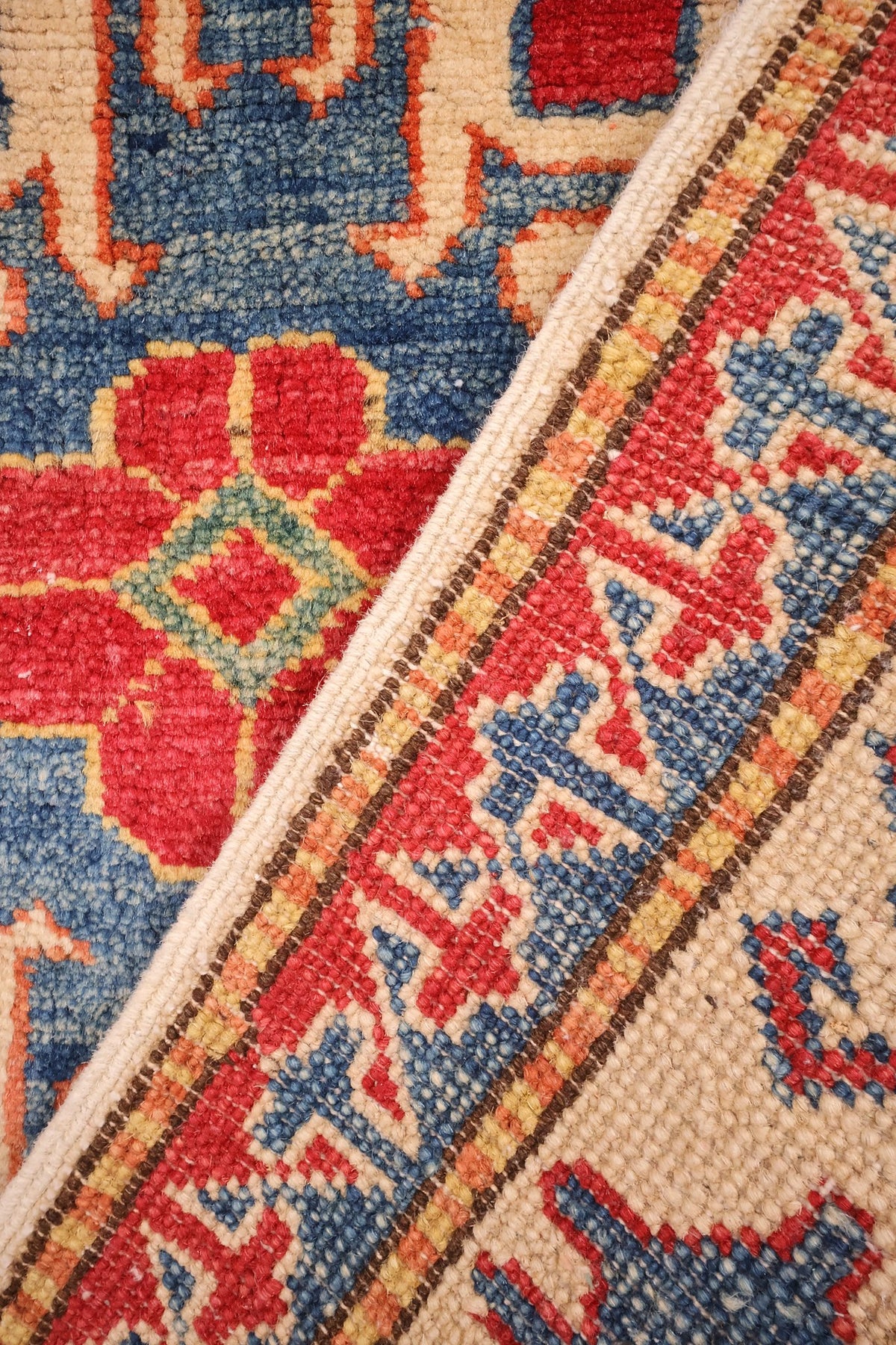 Envers du tapis Kazak noué à la main, nœuds de laine visibles le long du repli