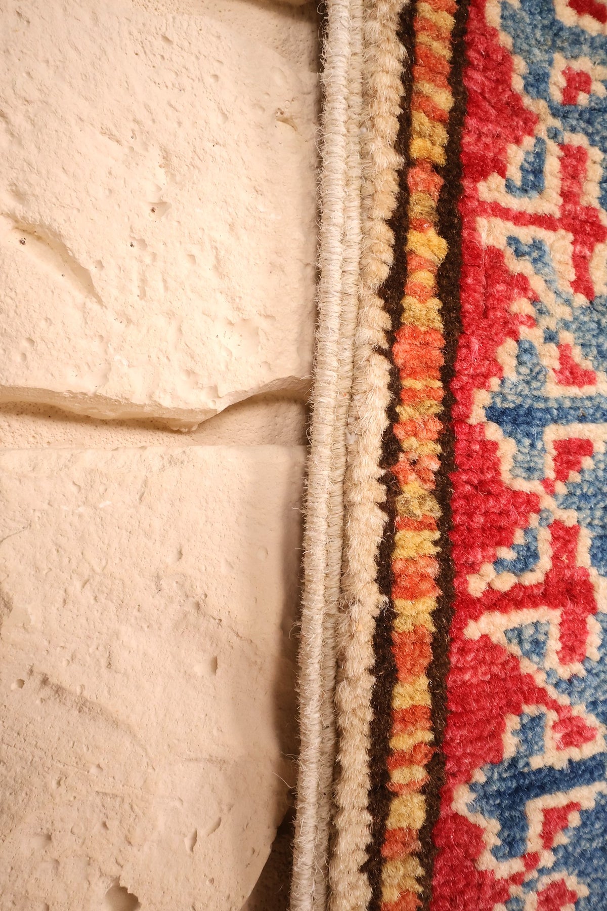Lisière et frange claire du tapis Kazak beige, bleu et rouge