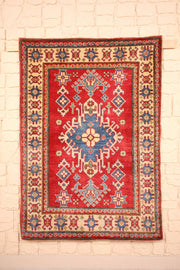 Tapis Kazak rouge 144 × 105 cm, vue d'ensemble avec médaillon central bleu à crochets