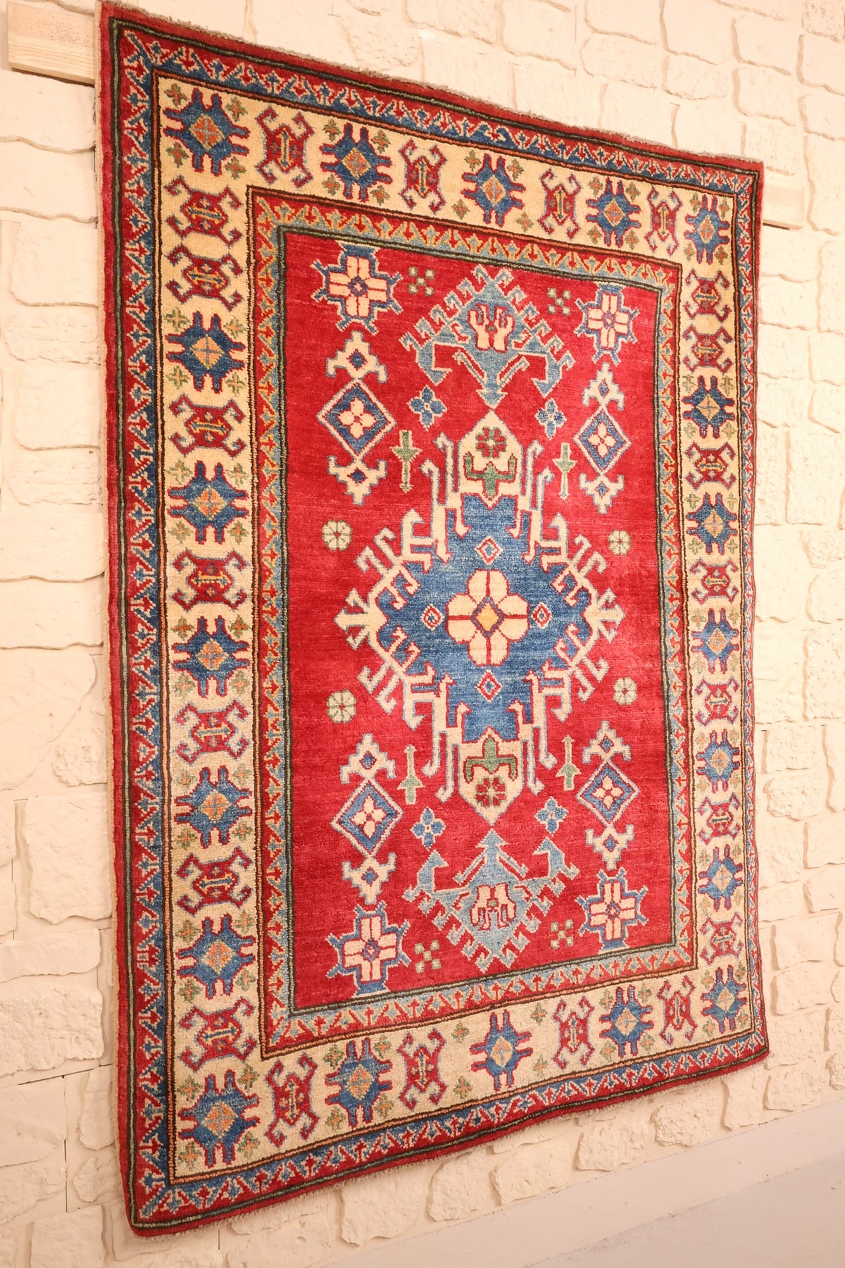 Tapis Kazak en laine nouée main, vue de biais du champ rouge et de la bordure ivoire
