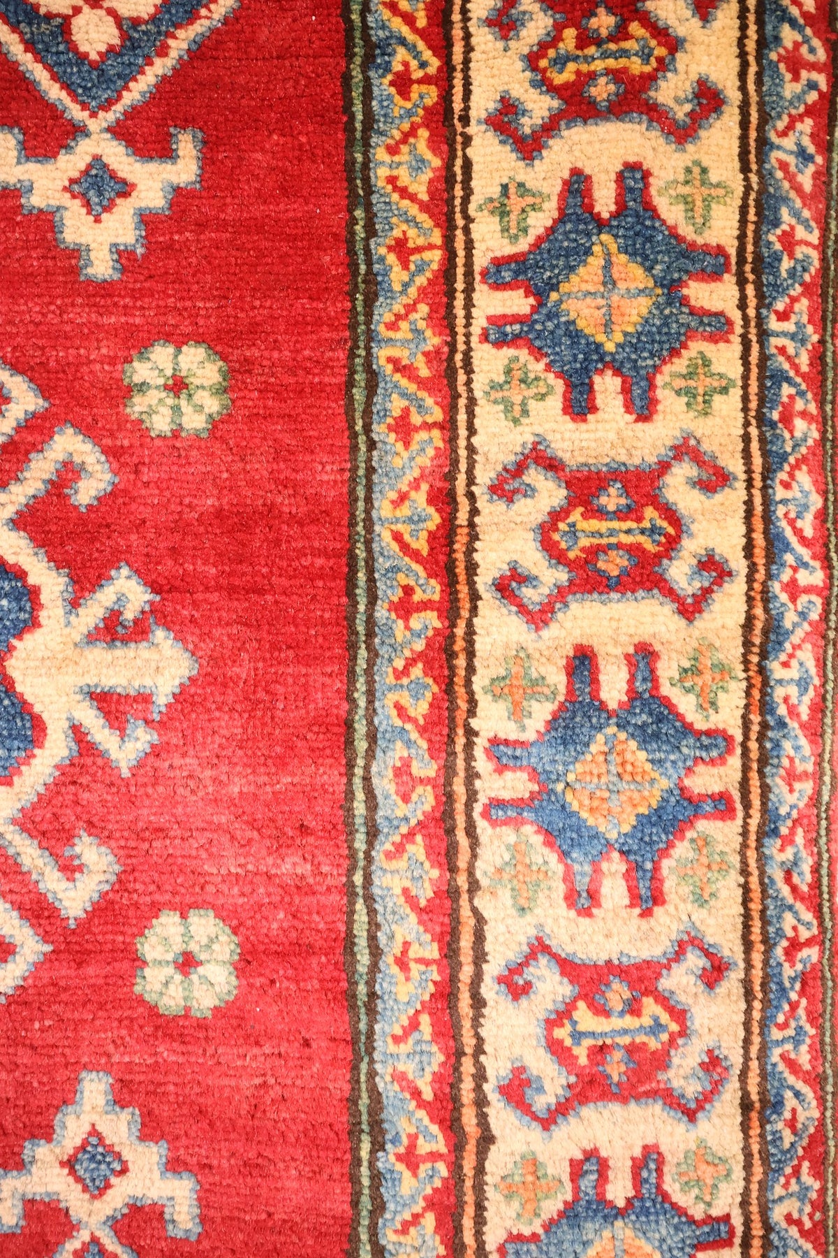 Bordure ivoire du tapis Kazak, médaillons bleus et rouges et contre-bordures à chevrons