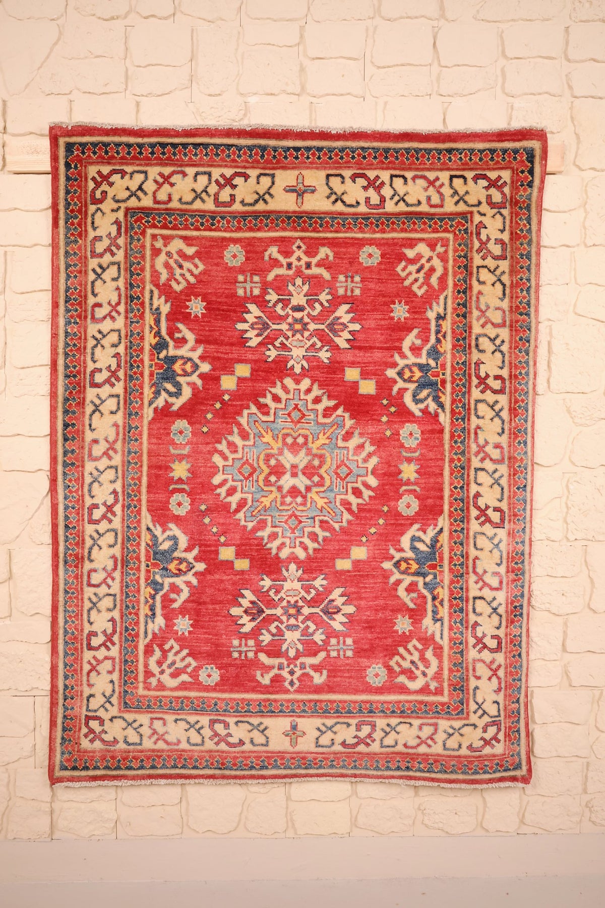 Tapis Kazak rouge 144 × 110 cm, vue d'ensemble avec médaillon étoilé ivoire et bleu